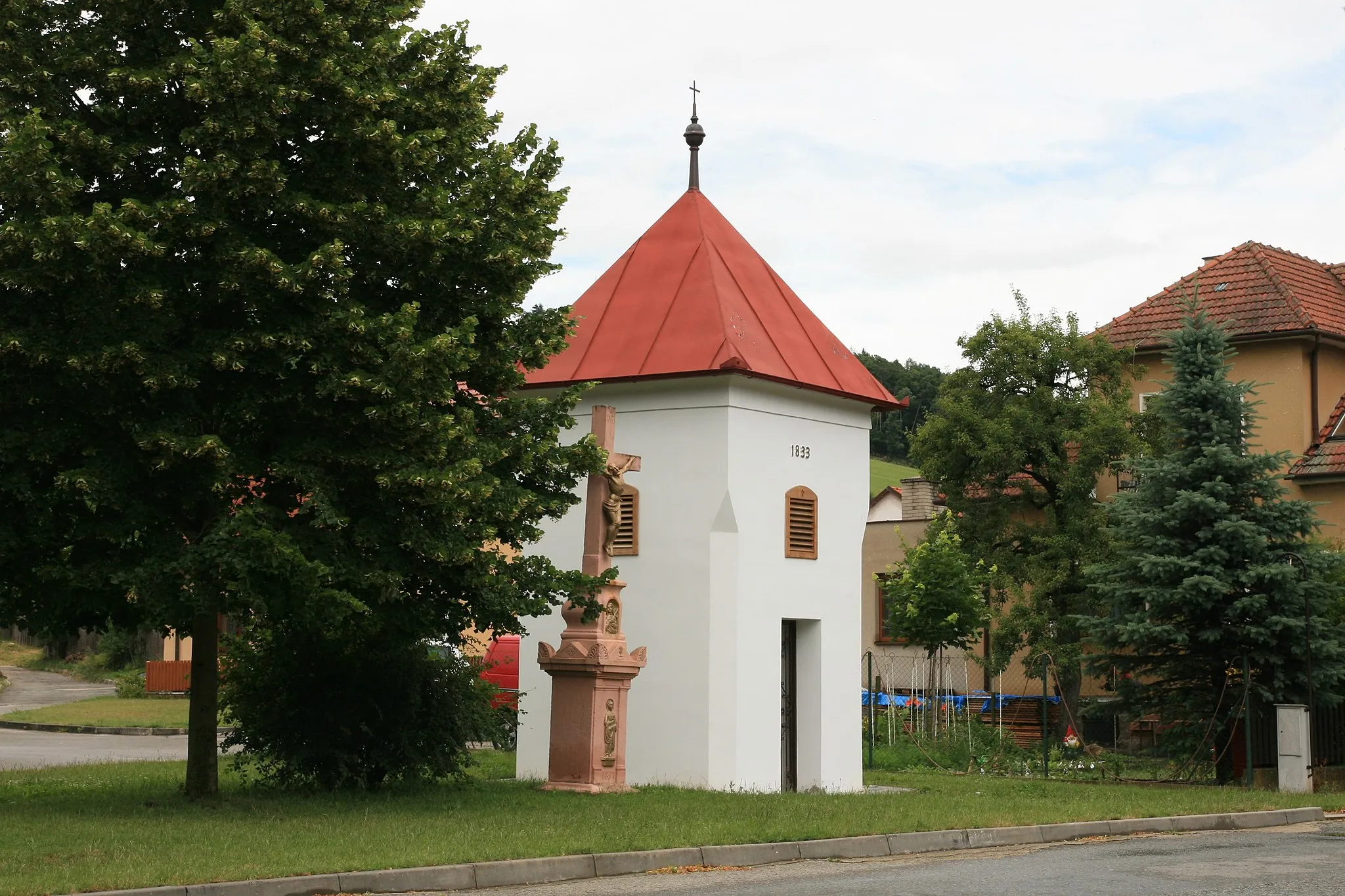 Photo showing: Závist (Blansko District), Czech Republic. Stone bell tower with a cross at the village green.