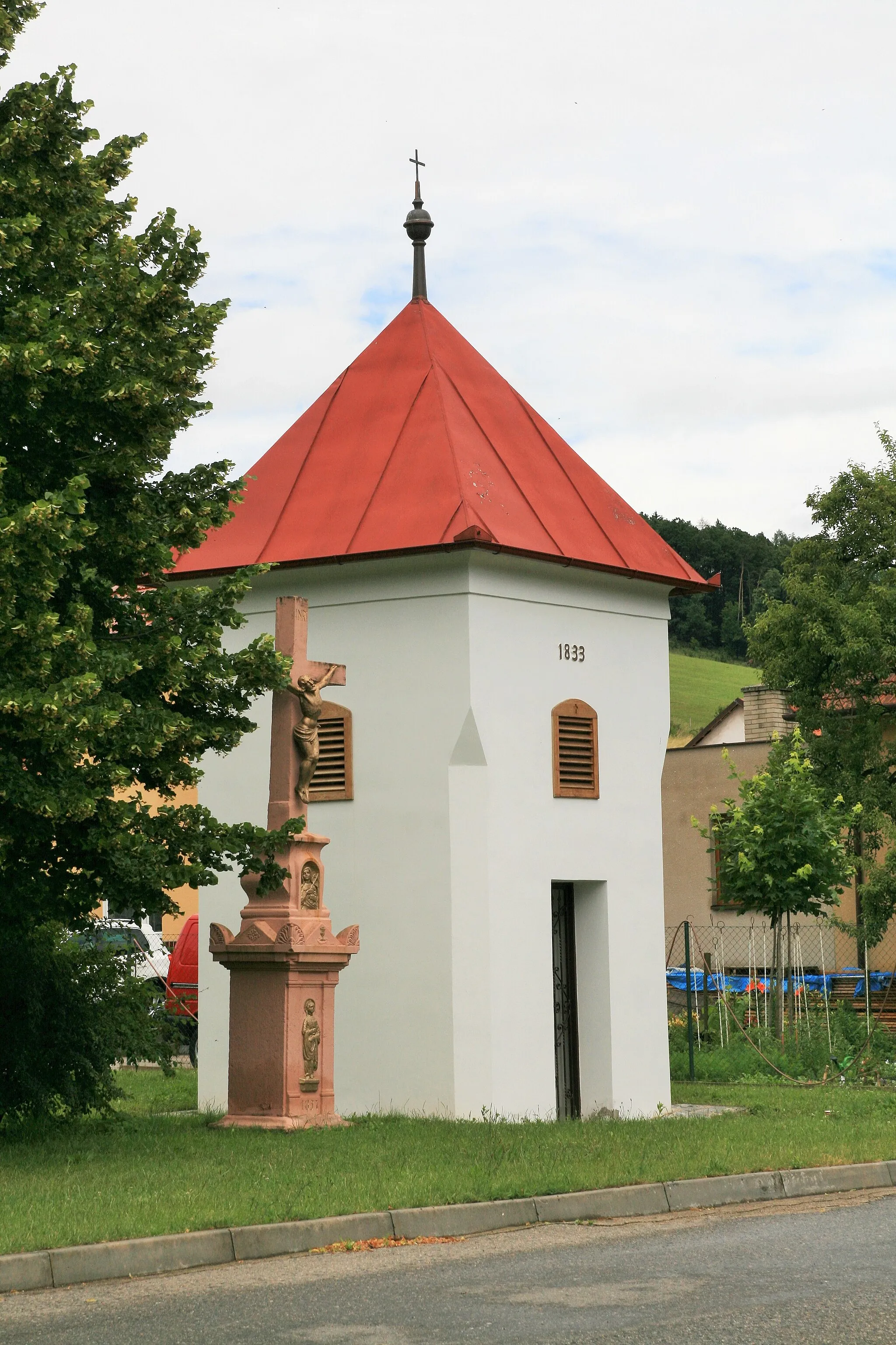 Photo showing: Závist (Blansko District), Czech Republic. Stone bell tower with a cross at the village green.