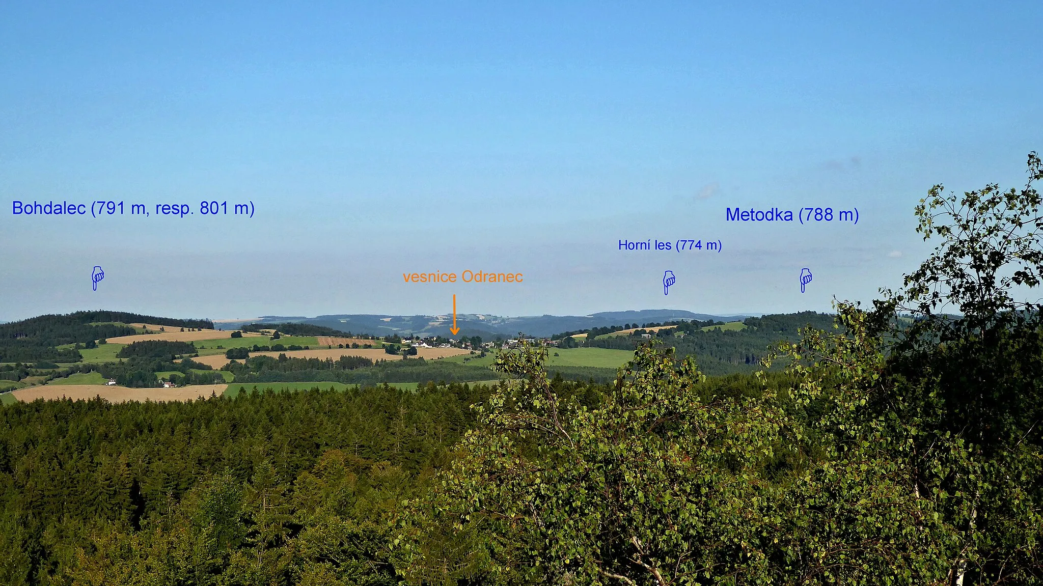 Photo showing: "Pasecká" Rock (819 m asl) is a rock formation in the geomorphological district "Pohledeckoskalská" Highlands and natural monument in the "Žďár" Hills Protected Landscape Area. The top part consists of three rock blocks with the czech names "Vyhlídka, Omšelý hřeben, Pernštejn". Adjusted output to a rock block called Viewpoint (czech name: Vyhlídka). The ending of the blue tourist route of the Czech Tourists Club, section: "Medlovský" pond – "Pasecká" Rock. A view from the rock block Viewpoint to the east: the hills with the names Bohdalec and Metodka, among them the settlement Odranec. On the horizon a ridge with the peak called Upper Forest (774 m asl), the highest peak in the geomorphological units "Sulkovecká" Highlands (district) and also in the "Nedvědická" Highlands (part of geomorphological whole "Hornosvratecká" Highlands). Photo-location: Czechia, "Vysočina" Region, small hamlet "Studnice", part of town "Nové Město na Moravě, "Pohledeckoskalská" Highlands, view from the rock of Viewpoint, "Pasecká" Rock (90°).