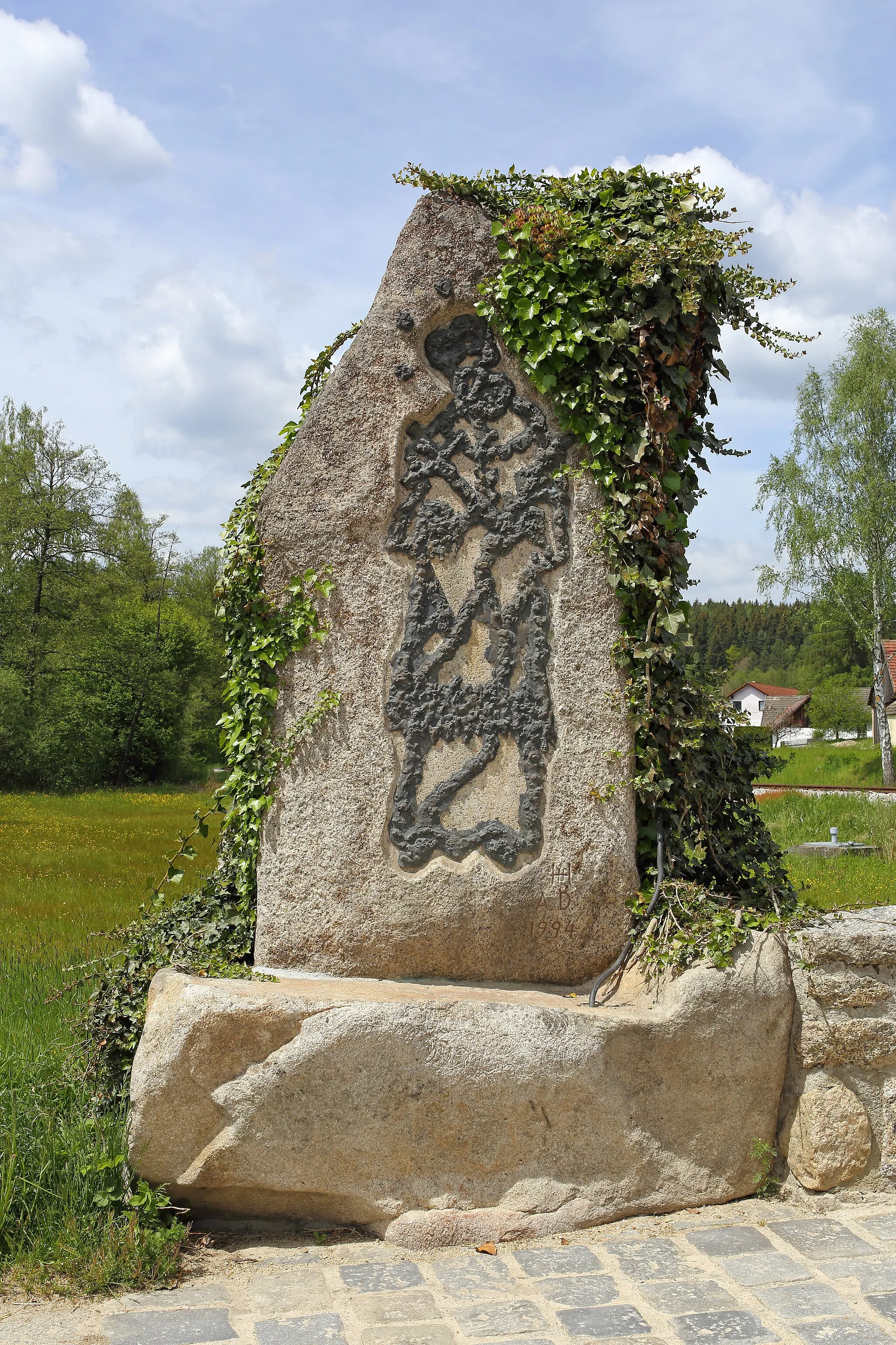 Photo showing: Bei der Brücke über den Reißbach in Schönau befindet sich ein Granitstein, auf dem die aus Eisen gefertigten Konturen Johannes Nepomuks angebracht sind.