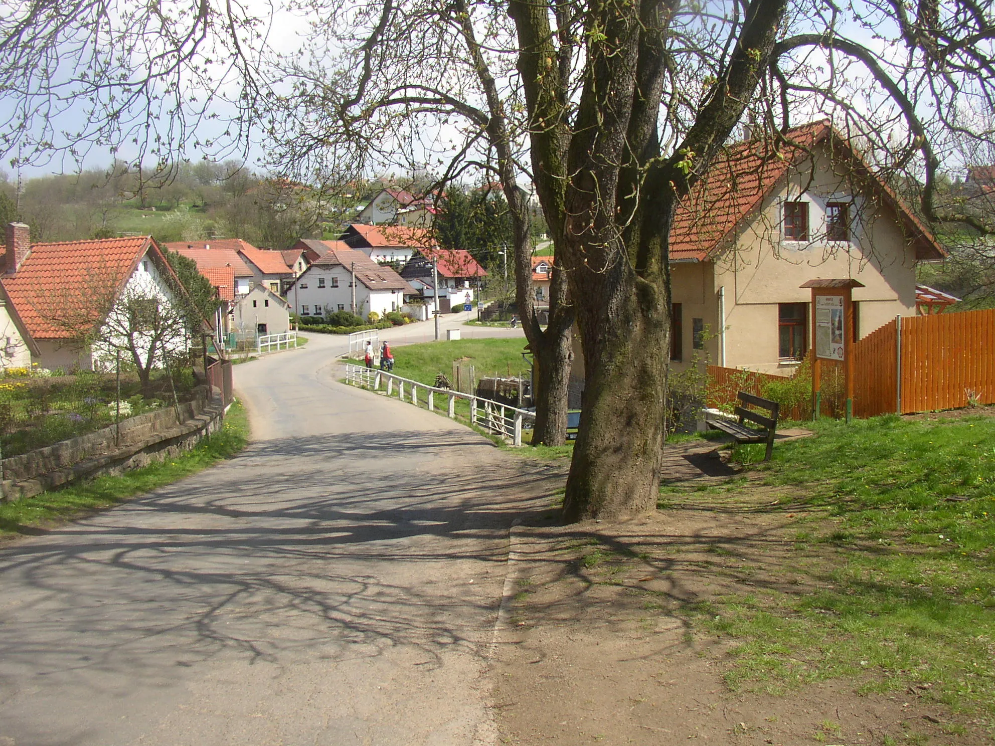 Photo showing: Hrusice, Prague-East District, Czech Republic. A view from centre of the village over valley of the Hrusický potok stream towards ENE. Right of the road there is house No 15 with a plaque from 1958 on the wall (left of the closest corner) commemoraing that Josef Lada was born here. The original house was replaced with a newer edifice in 1932.