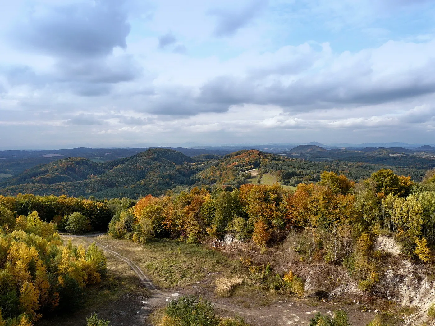 Photo showing: Housecké vrchy a Kokořínsko z Vrátenské hory: zleva Uhelný vrch, Drnclík, Špičák (Lipový vrch a Zámecký vrch jsou v zákrytu); v popředí trachytový lom