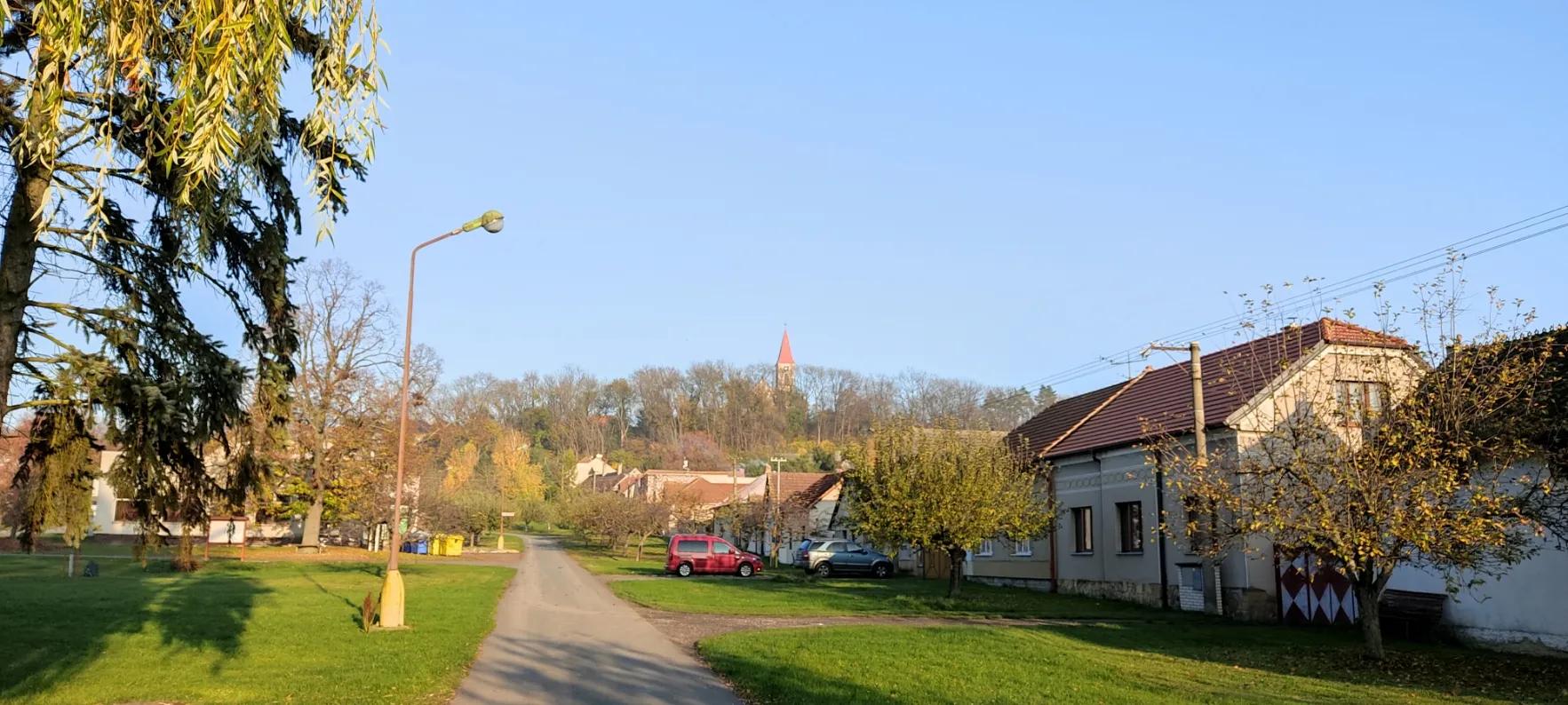 Photo showing: The village square and church in the background in Vrbice, Nymburk District, Central Bohemian Region, Czech Republic. Photo taken on 7 November 2020.