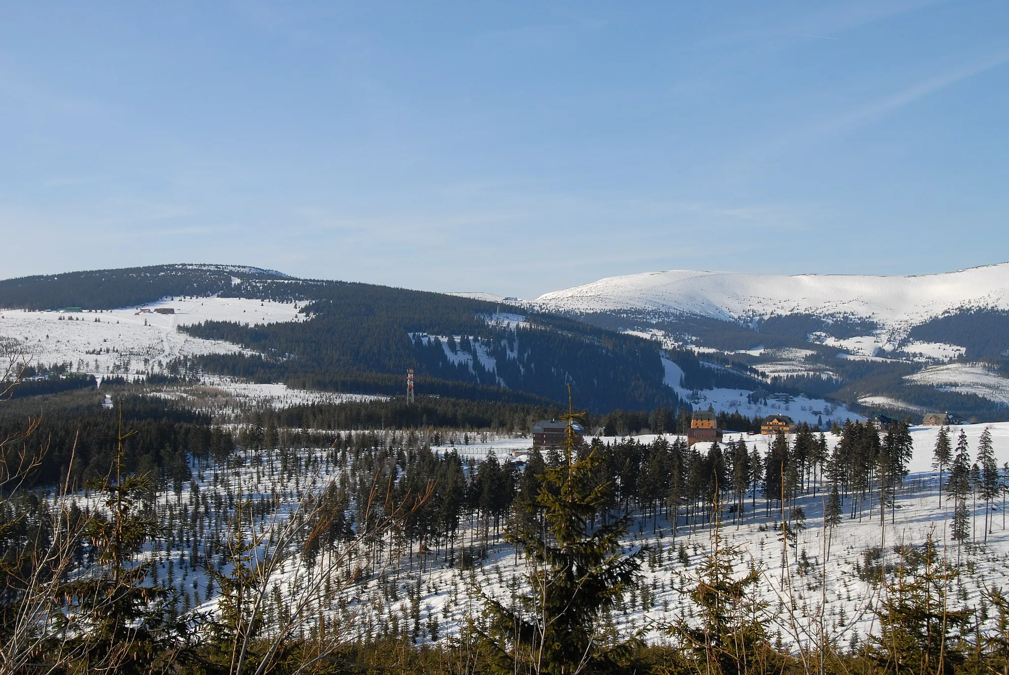 Photo showing: Pohled z modré turistické trasy na úbočí Černé hory (1299 m.n.m.):Zprava: nad lesem Lesní bouda, nad ní Liščí hora a na ní Lyžařská bouda, vysílač Lučiny (1084 m.n.m.), nad ní sjezdovky na Vysokém Svahu nad Pecí pod Sněžkou, nad nimi rozhledna na Hnědém vrchu, výše chata Výrovka, v pozadí Modrý důl a dole pension Oddech, Lidická bouda a bouda Slovanka