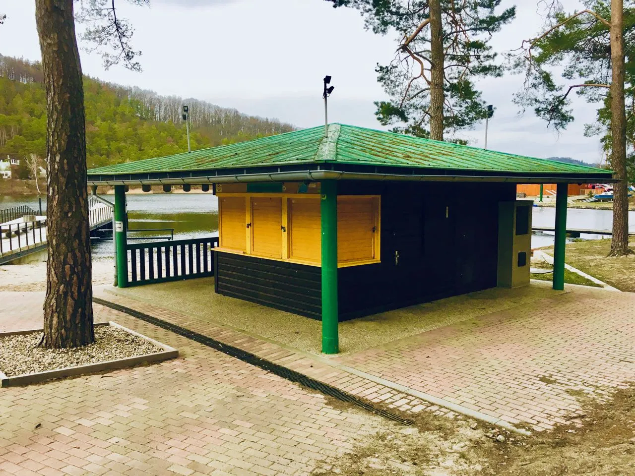 Photo showing: Plážový novinový kiosek je jedním z příkladů hodnotné a kompaktní účelové zástavby kolem Máchova jezera. Postaven ve 20. letech 20. stol., svému účelu slouží dodnes.