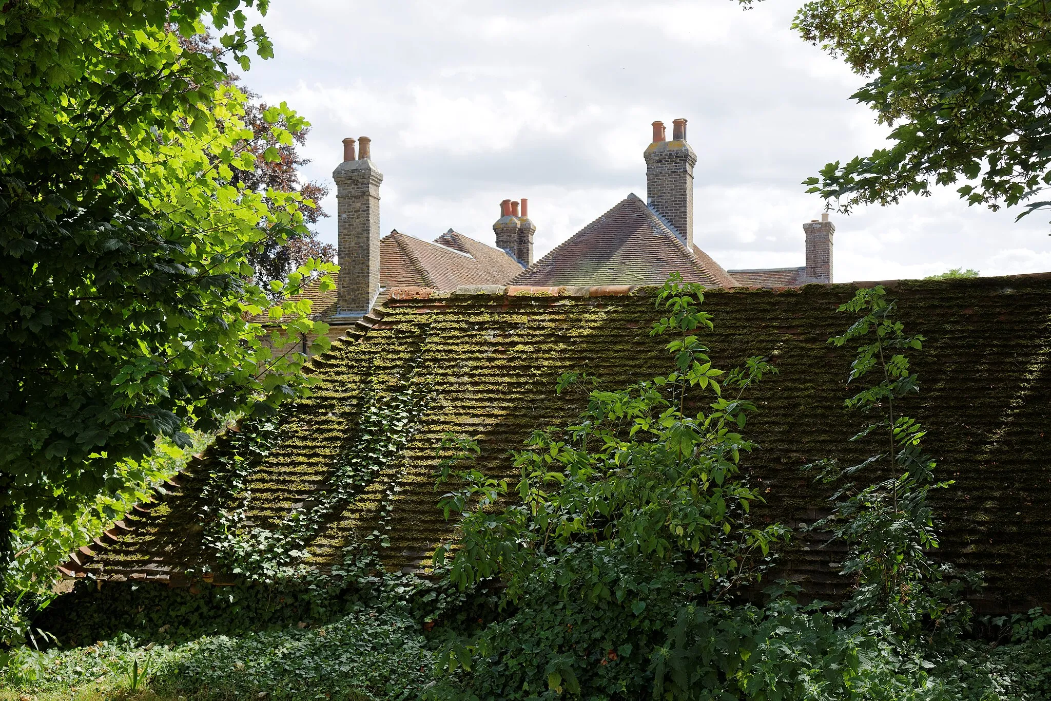 Photo showing: Mossy roof of a barn and house chimneys on Monkton Street in Monkton, Kent, England. Camera: Canon EOS 6D with Canon EF 24-105mm F4L IS USM lens. Software: RAW file lens-corrected, optimized, perhaps cropped, and converted to JPEG with DxO OpticsPro 11 Elite, and likely further optimized with Adobe Photoshop CS2.