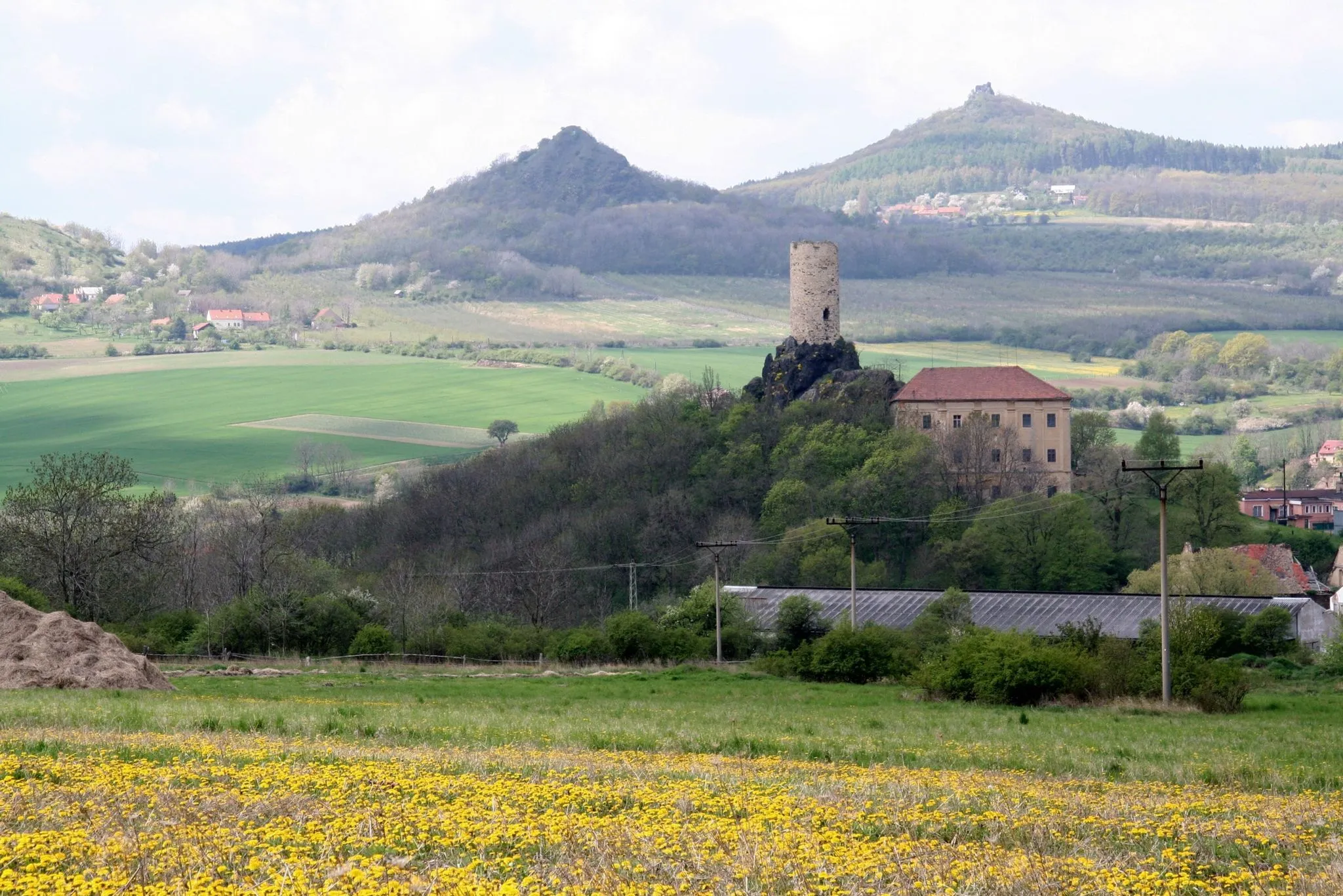 Photo showing: České středohoří, Czech Republic. A view from Sutom over Skalka Castle in Vlastislav towards WSW with hills of Plešivec (centre) and Oltářík (right) in the background.