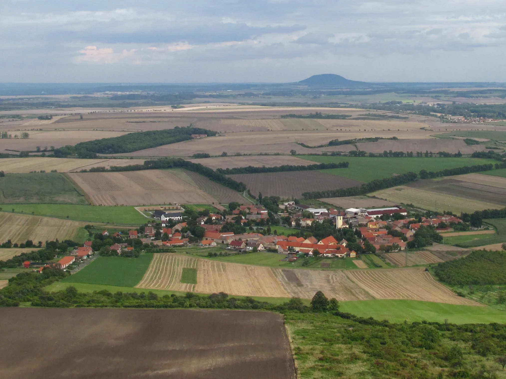 Photo showing: Slatina village an Řip hill on the horizon as seen from Hazmburk Castle (ruin), Litoměřice District, Czech Republic.