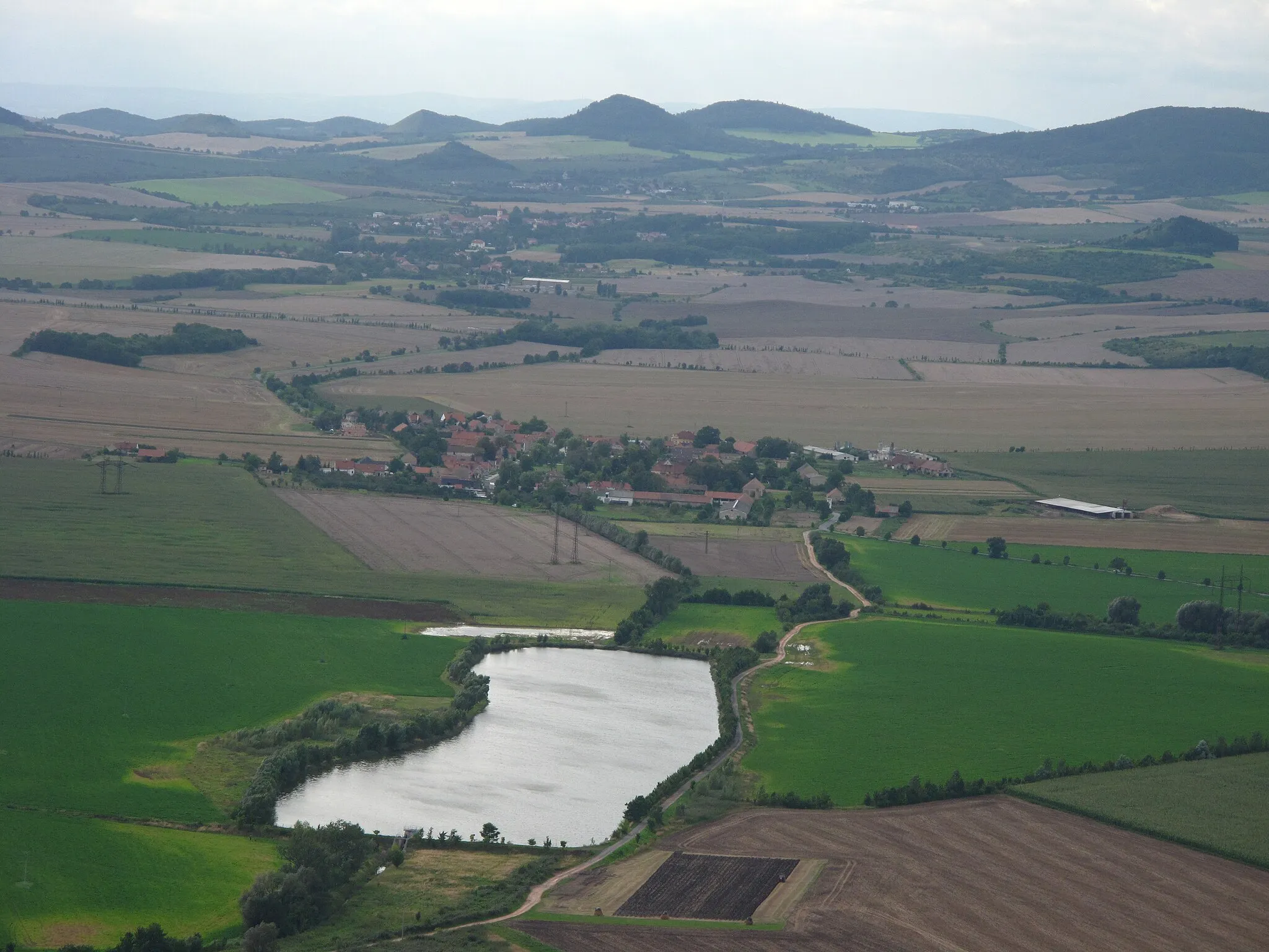 Photo showing: Pond on Rosovka Stream, Lkáň village and Solany village (background) as seen from Hazmburk Castle (ruin), Litoměřice District, Czech Republic.