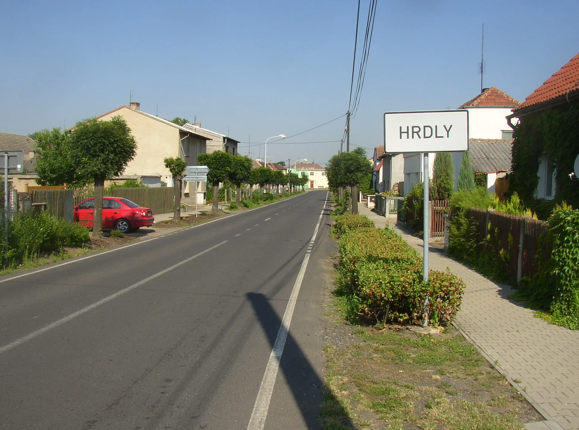 Photo showing: Hrdly, Litoměřice District. A view from vicinity of Dolánky/Oleško crossroads along the main street in WNW direction towards centre of the village.