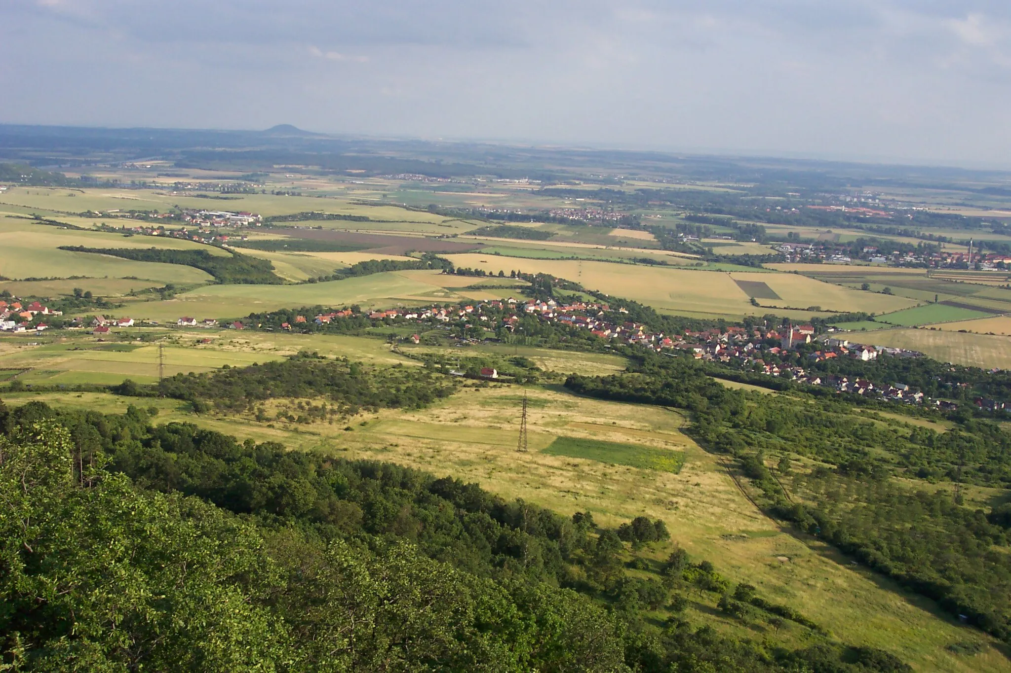 Photo showing: A view from the Dlouhý vrch near Litoměřice towards SSE. In the foreground village of Žitenice and small part of Pohořany (left). In the very right eastern edge of Litoměřice town with fortress town of Terezín beyond. Slightly right off the centre of the image České Kopisty. In the left villages of Podviní and Trnovany, then line of trees indicating course of the Elbe (itself obscured by terrain). On the oposite bank of the Elbe village of Počaply, then large Travčice Forest and Říp Mountain on the horizon. Next to the left corner of the forest village of Nučničky, in front of its right part village of Travčice.