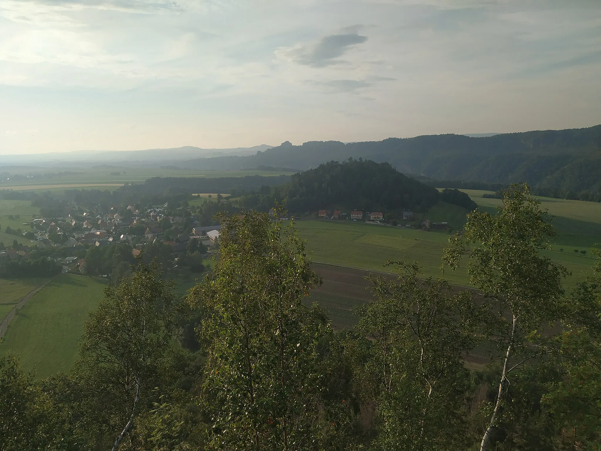 Photo showing: Blick vom Zirkelstein auf die Kaiserkrone und das Dorf Schöna. Im Hintergrund stehen die Schrammsteine.