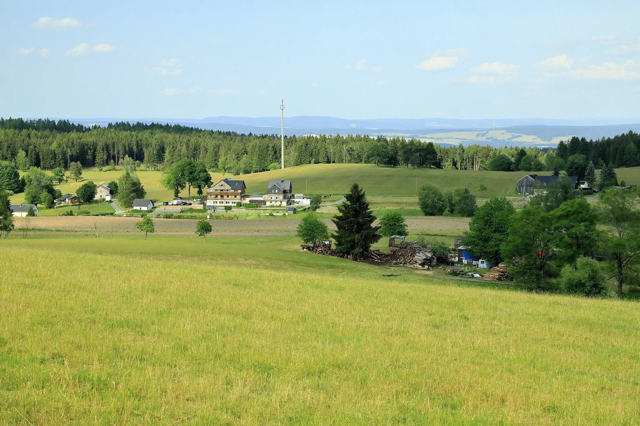 Photo showing: Vom Weg zur Elsterquelle Richtung Nordost, der Funkmast mit der Position 50.1968517N, 12.2924894E ist ein gut auffindbarer Orientierungspunkt.
Durch die Lage an den seit Kriegsende 1945 mehrere Jahrzehnte nur sehr restriktiv passierbaren Grenzen waren die Gebietszipfel von Bad Brambach und Schönberg sowie Asch ausgesprochen abgelegen und das ist auch fünfzehn Jahre nach der Liberalisierung durch die Schengener Union noch spürbar.