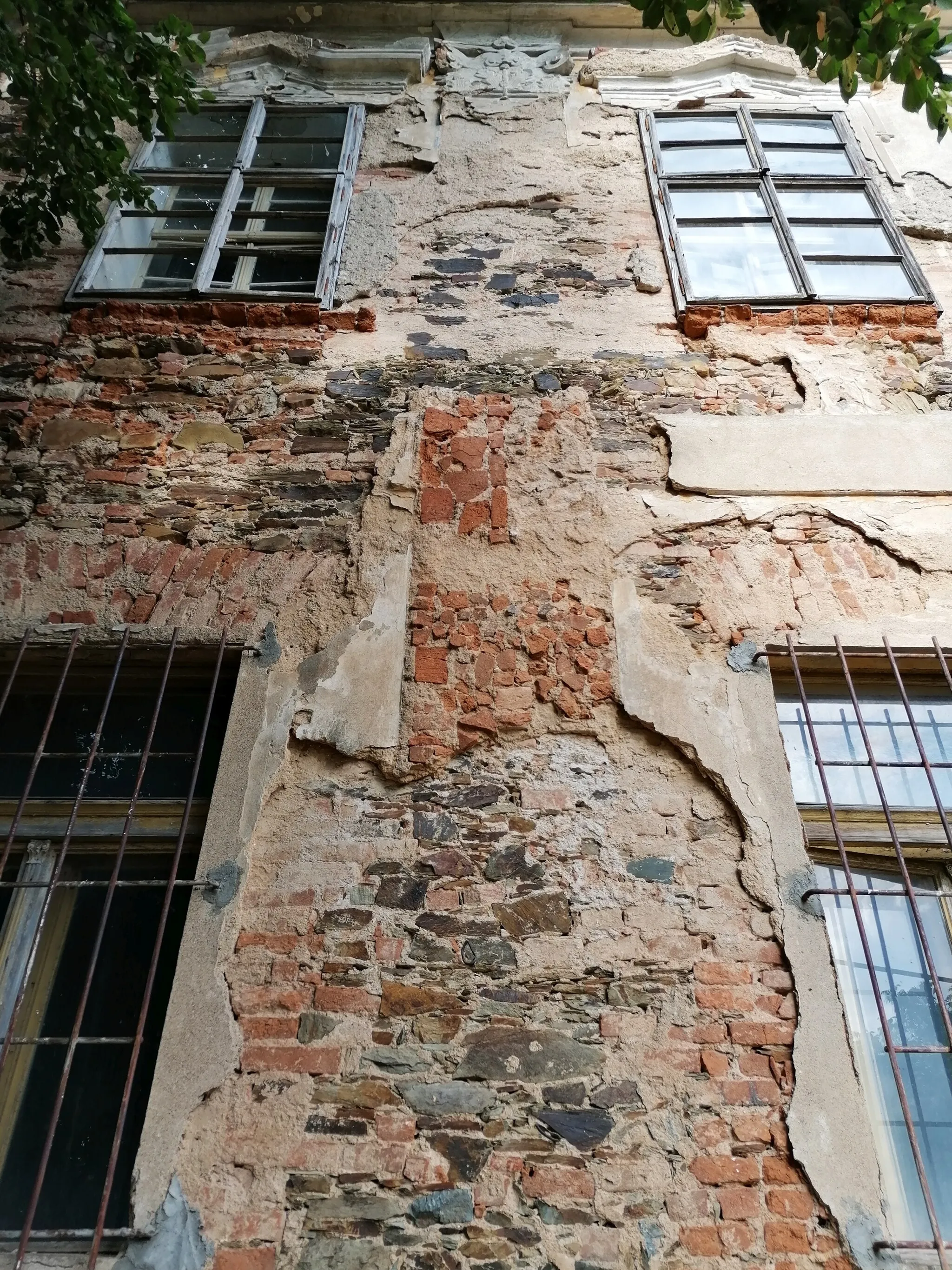 Photo showing: Chříč (okres Plzeň-sever), zámek (20220827), detail severní části západního průčelí. Příklad degradace omítek a zdiva historické stavby, která je dlouhodobě bez využití a údržby.