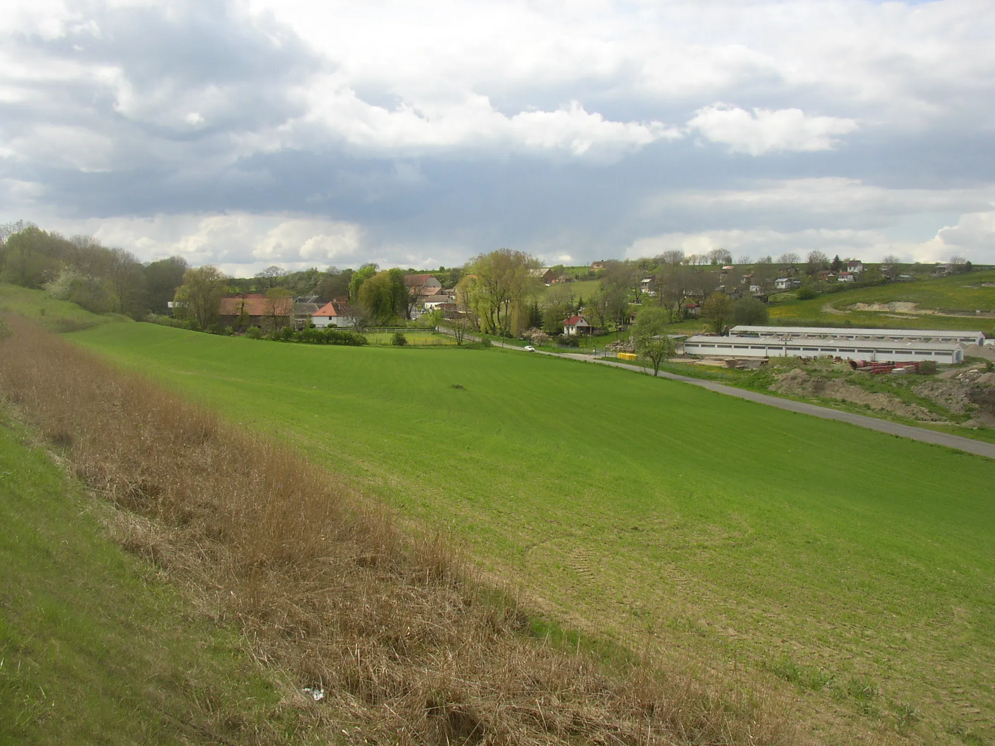 Photo showing: Netovice, part of Slaný town, Kladno District, Czech Republic. A general view of the village from the Southeast, from bridge of R7 expressway.