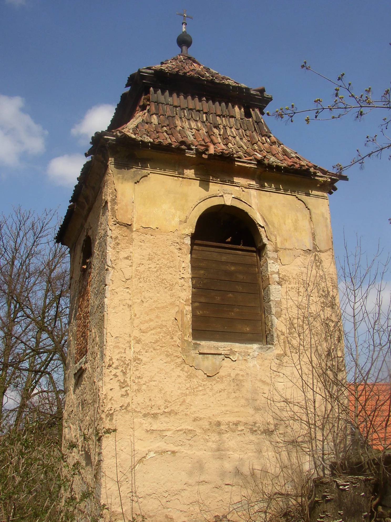 Photo showing: Koleč Chateau, Kladno District, Czech Republic. Belfry from 1779 next to SE corner of the Holy Trinity Chapel as seen from the south. Only part of the building from first floor up is visible, a terrain step hides the groundfloor from this point of view.