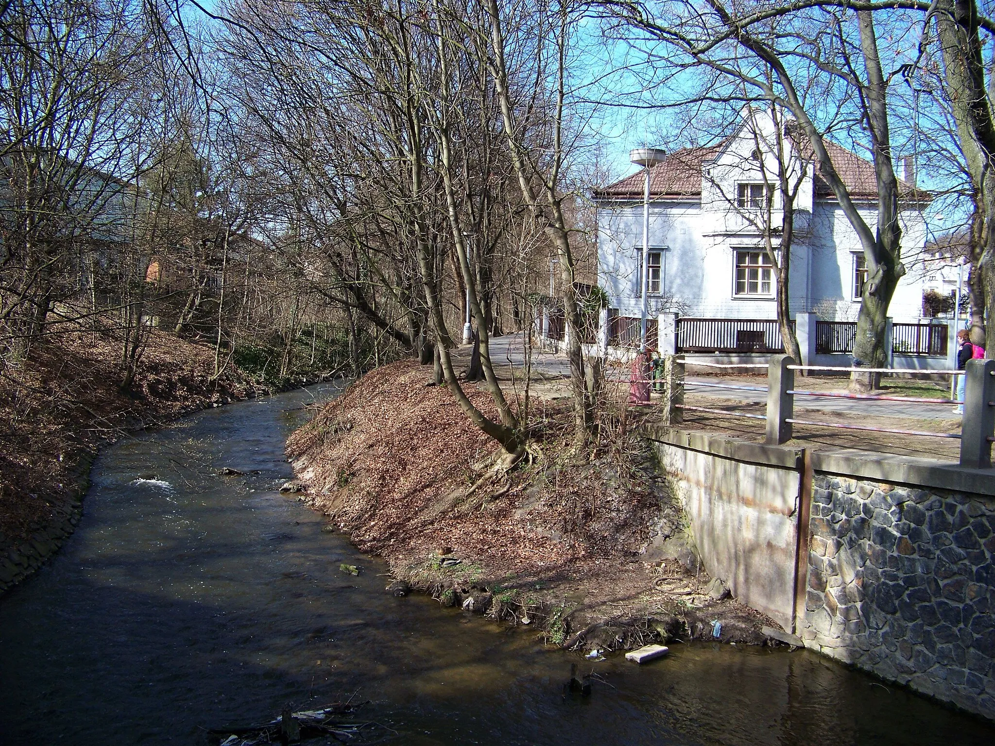 Photo showing: Kralupy nad Vltavou, Mělník District, Central Bohemian Region, the Czech Republic. Zákolanský Creek, Masnerova stezka and house Jana Palacha 659/1, seen from a bridge of Chelčického street.