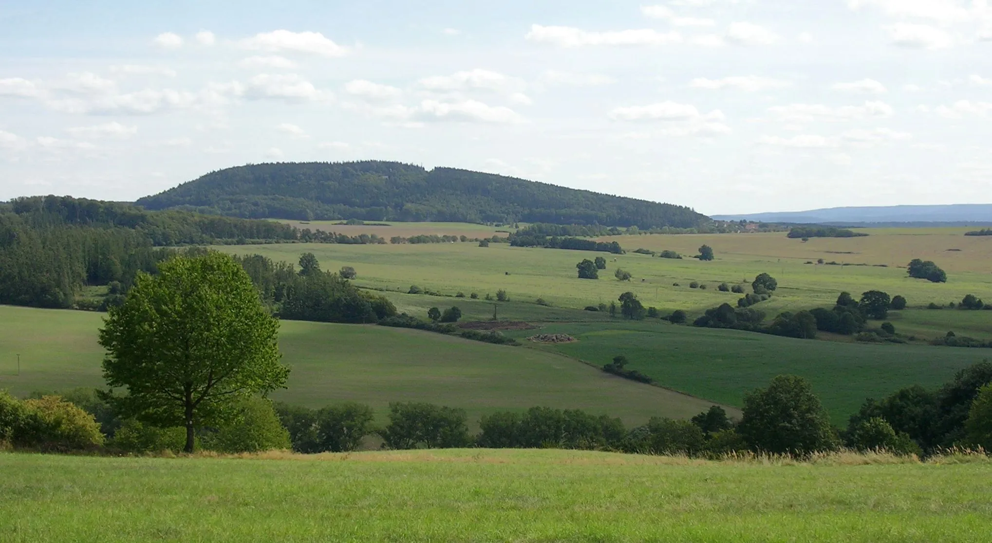 Photo showing: Rakovník District and Beroun District, Central Bohemian Region, the Czech Republic. A views of Velíz Hill from Špička Hill.