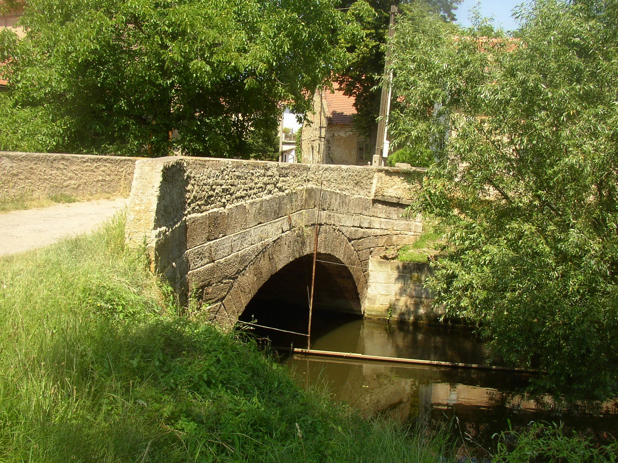 Photo showing: Doksany , Litoměřice District, Czech Republic. Small stone arch bridge over the millrace next to the mill.