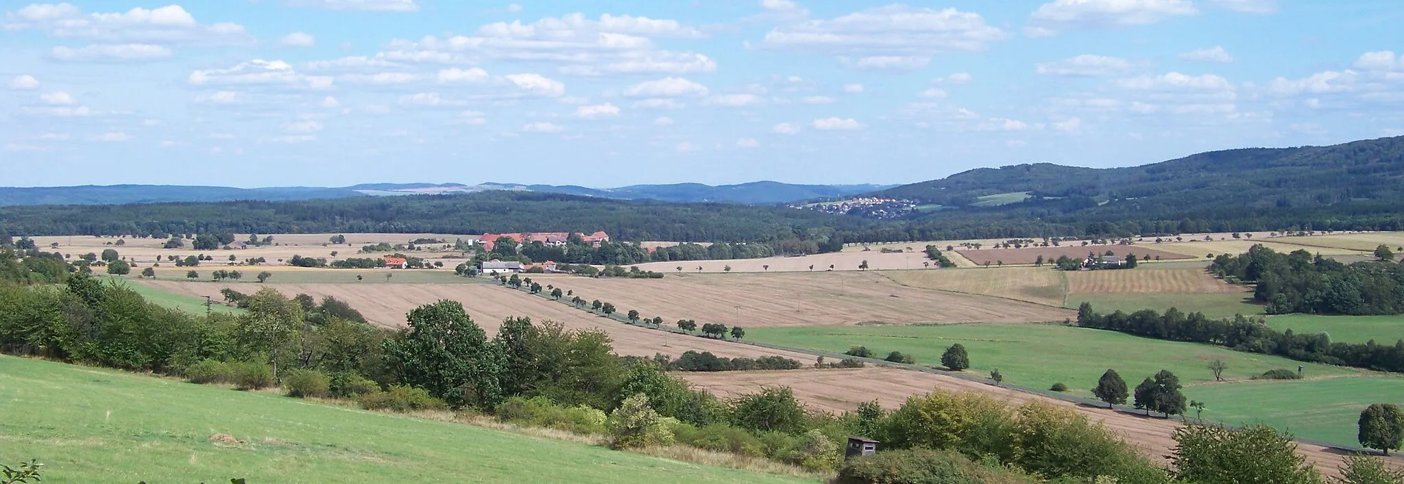 Photo showing: Rakovník District and Beroun District, Central Bohemian Region, the Czech Republic. A views of villages of Karlov and Nový Jáchymov and of Hudlický vrch Hill from Špička Hill.