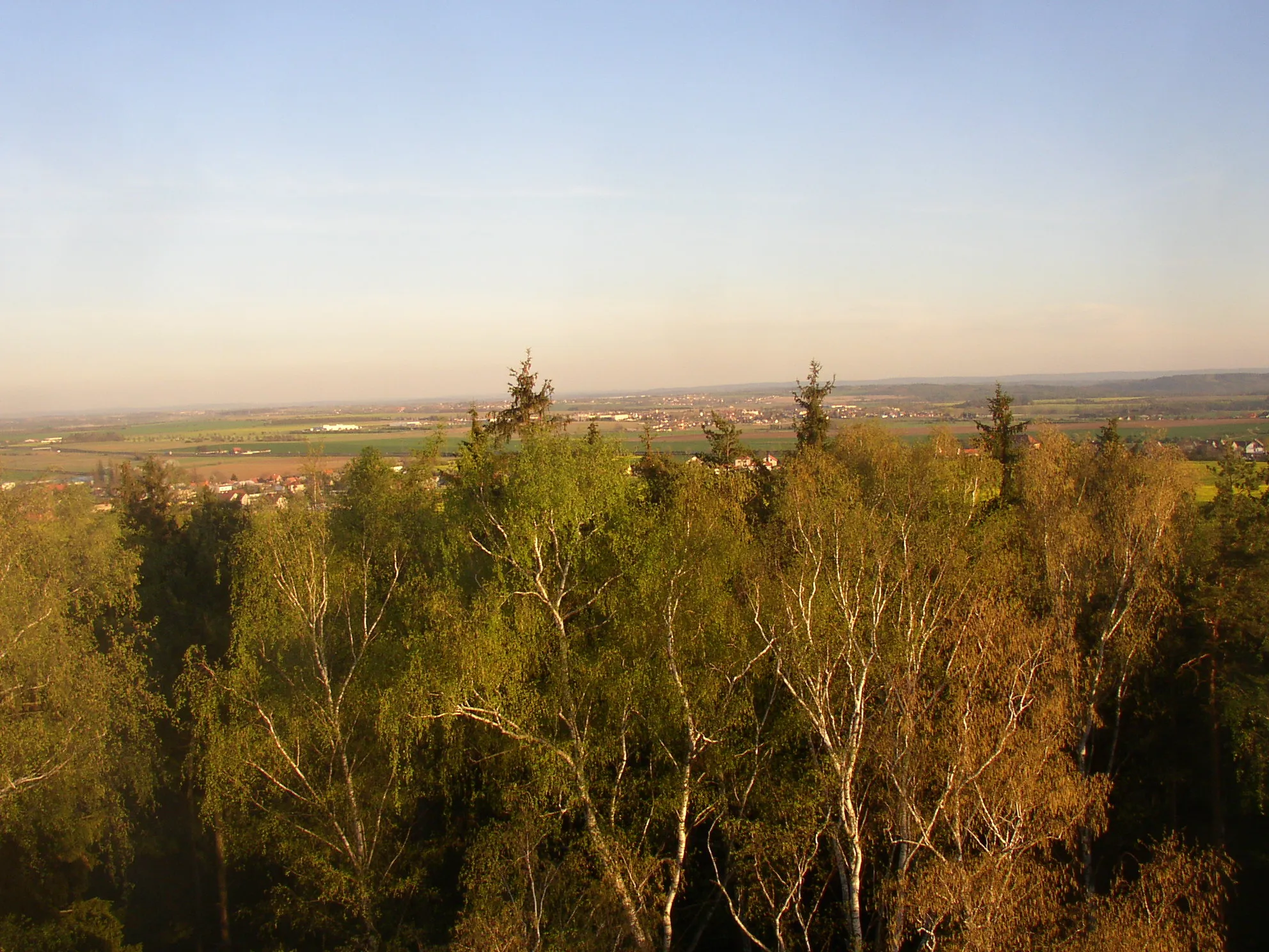 Photo showing: View from Kožova hora lookout tower in Kladno towards SE/SSE. In the left foreground Pletený Újezd (left) and Braškov (right), town of Unhošť is visible between tree tops in the middle.