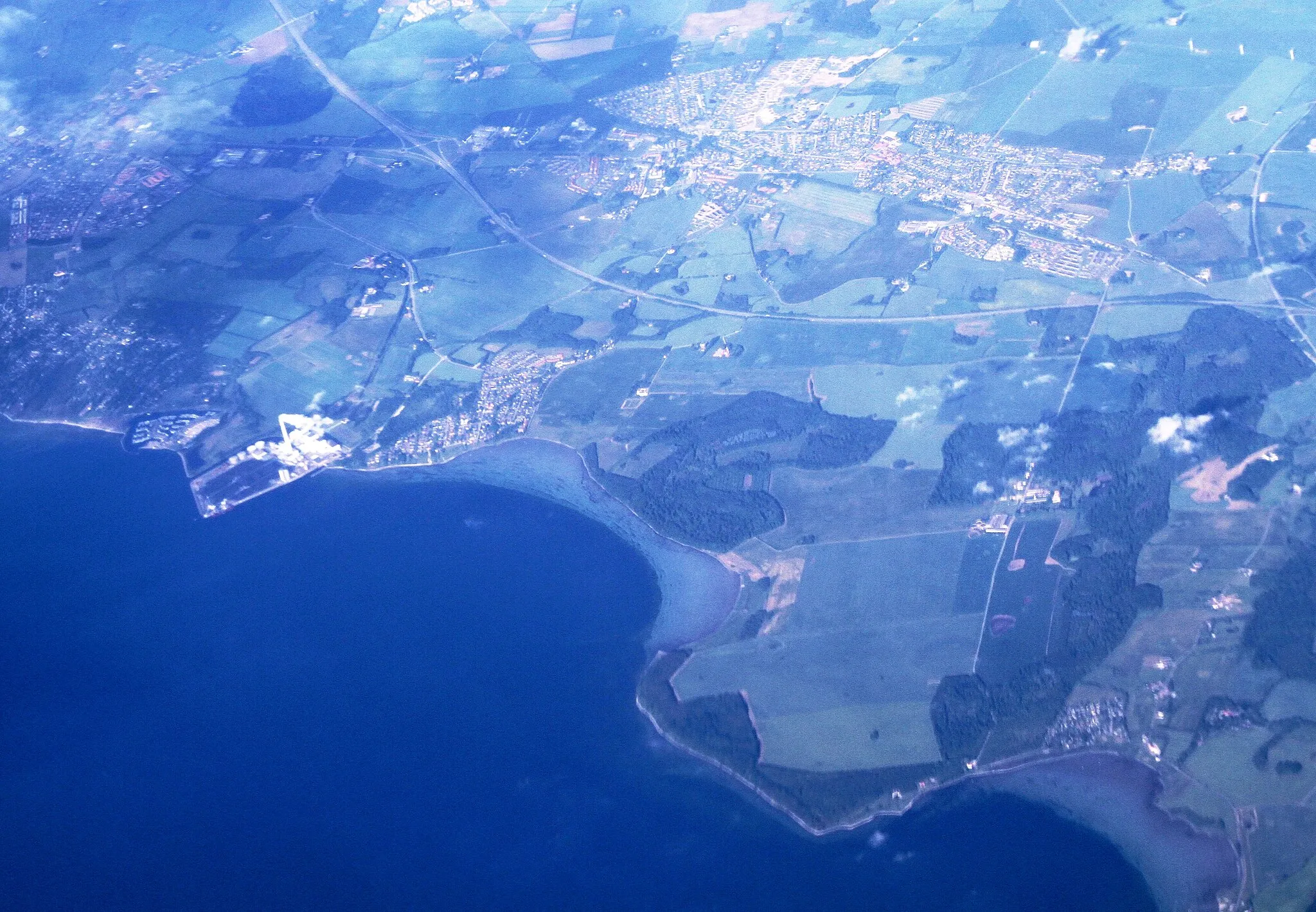Photo showing: Area southeast of Aarhus, Denmark. The white facility is the Studstrupværket power plant. The village is Skødstrup.