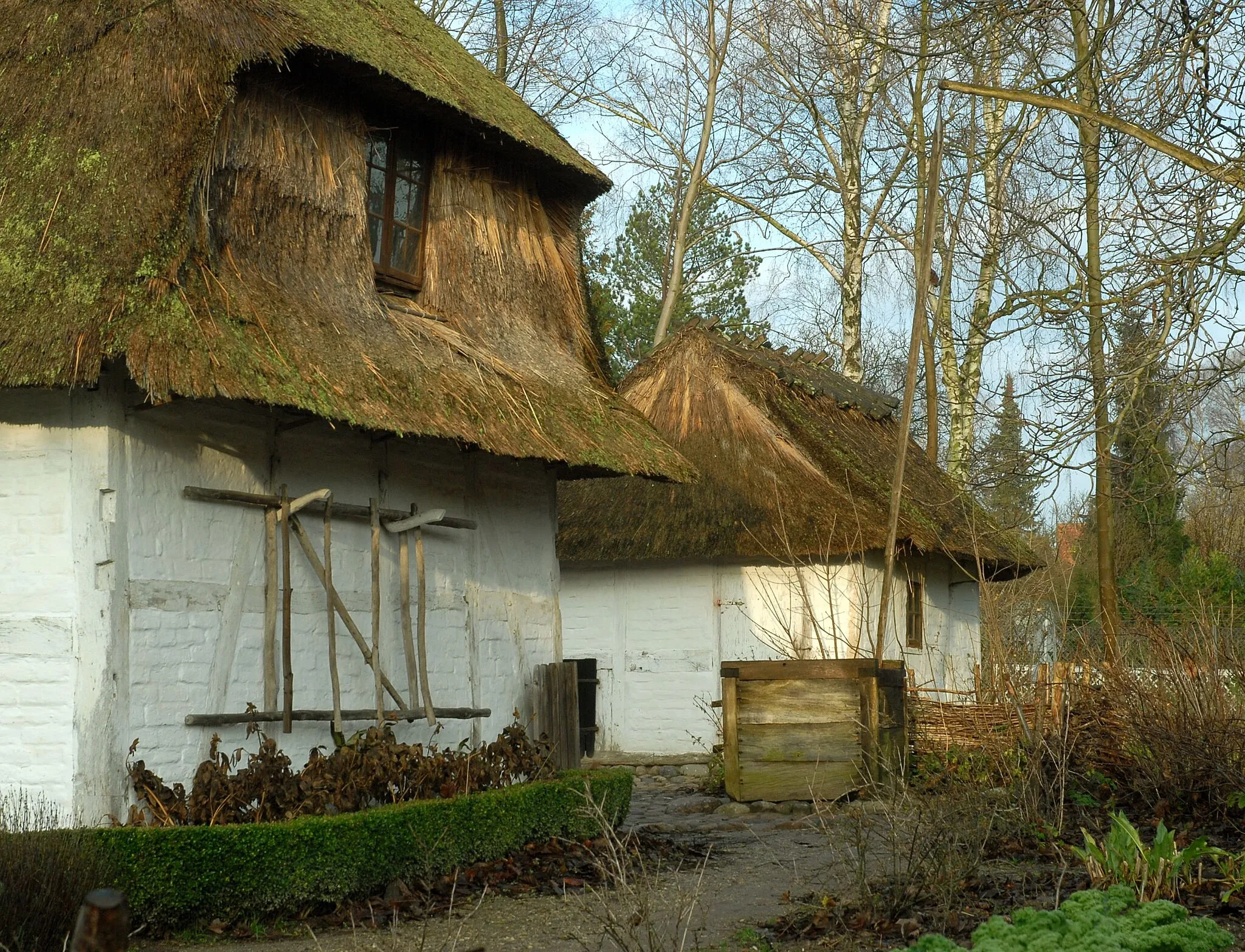 Photo showing: Stuehusets gavl med skyne og hængende lad. Bag brøndkarmen huggehuset