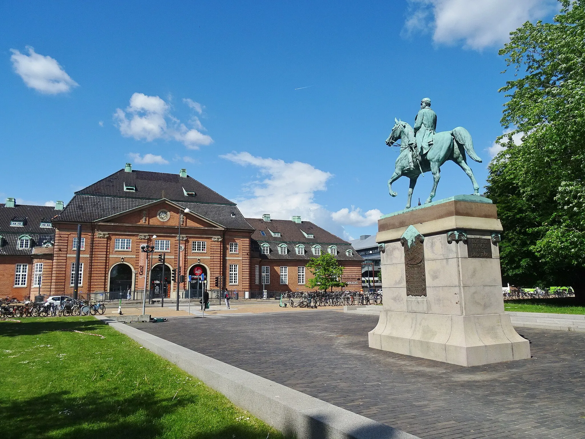 Photo showing: At the left the former railway station of Odense in Denmark. At the right an equestrian statue of king Christian IX from 1912 by Aksel Hansen (1853-1933).