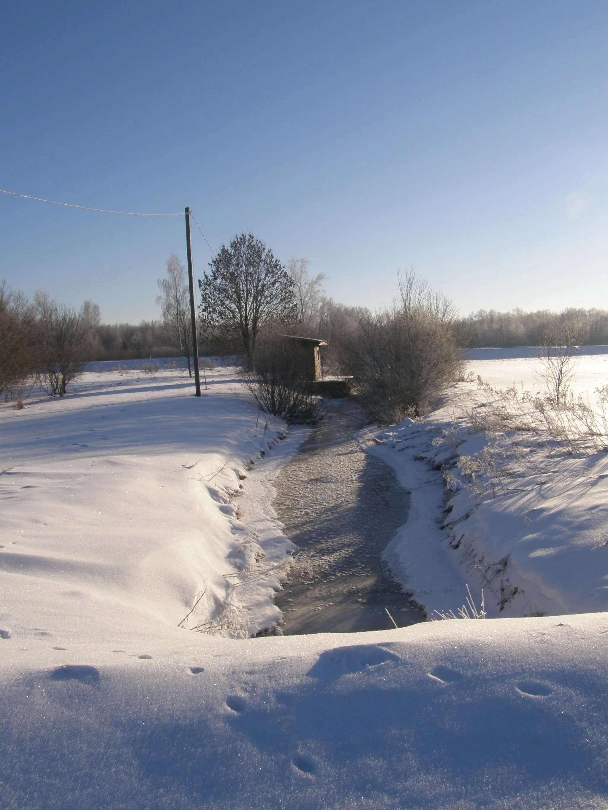 Photo showing: Räpu jõgi Arkma külas, vaade allavoolu. Taamal näha ka Arkma hüdrokeemiaseire jaam.