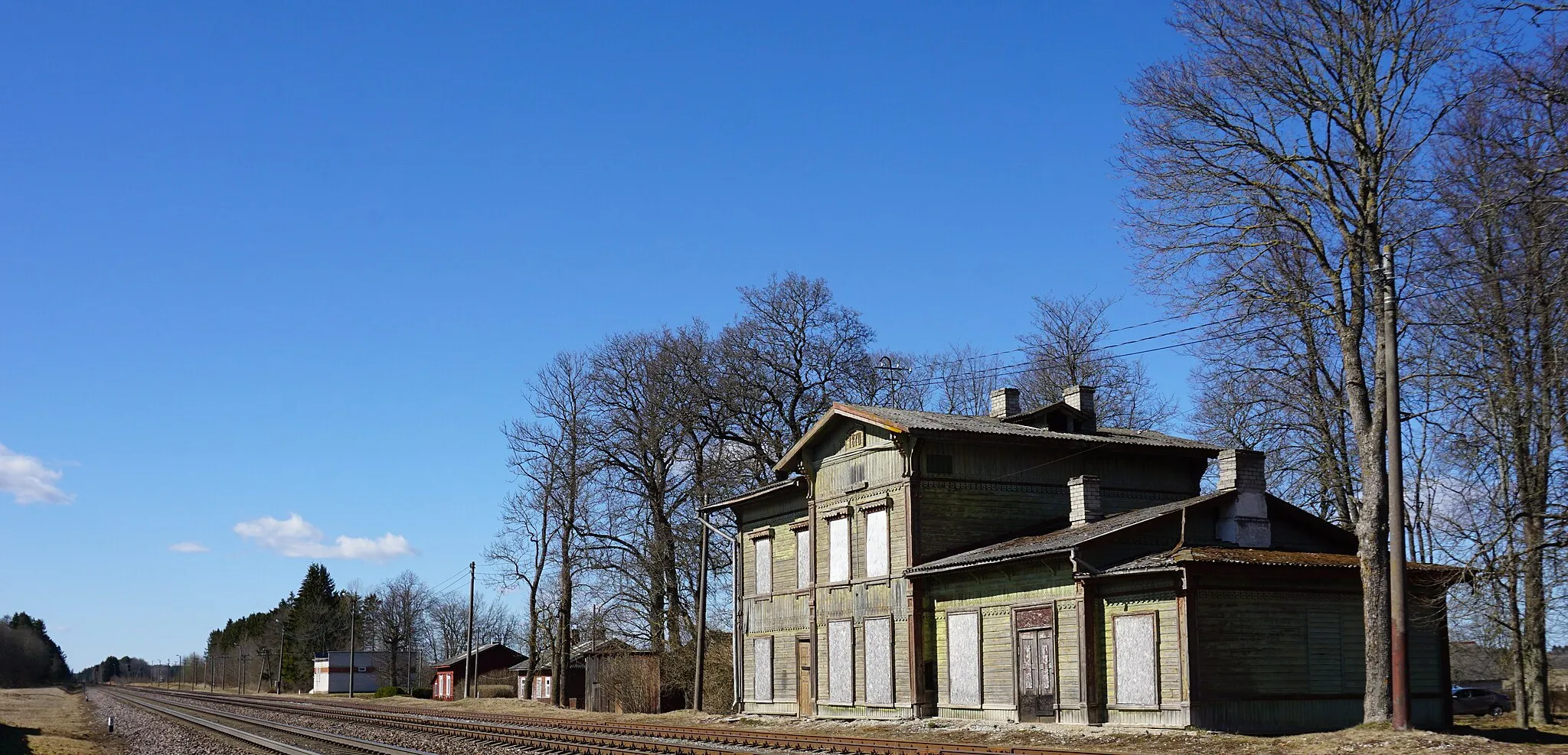 Photo showing: Kabala raudteejaam Tapa-Narva liinil. Kabala jaamahoone valmis koos raudteega 1870. aastal ja on koos abiehitistega silmapaistvalt autentsena säilinud tänaseni. Kahekorruseline kroonuhistoritsistlik puithoone ehitati III-IV klassi jaama tüüpprojekti järgi sarnaselt Paldiski, Keila, Raasiku jmt jaamahoonetega. Jaamahooneid iseloomustab madal viilkatus ja asümmeetriline pikifassaad, mille kõrgem viiluga keskosa jagab maja ühe- ja kahekorruseliseks tiivaks.
Erinevalt teistest sama tüübi jaamahoonetest on Kabala jaamahoone mõlema külje keskviilul tänaseni säilinud number raudtee avamise aastaga: "1870", silmapaistvalt hästi on säilinud ka hoone asulapoolse külje dekoor, ehkki amortiseerunud katuse tõttu esineb hoonel silmnähtavaid veekahjustusi. Sisse on langenud jaamahoone ootesaali lagi. Kuigi hoone omab suurt väärtust ning vääriks säilitamist on ehitise elujõulisus ja kasutusperspektiiv küsitavad.
2000. aastate algusest seisab jaamahoone tühjalt ja on järjest halvenevas seisukorras.

2019. aastal avaldatud nimekirja kohaselt kuulub Kabala jaamahoone ehitiste hulka, millest Eesti Raudtee soovib vabaneda.