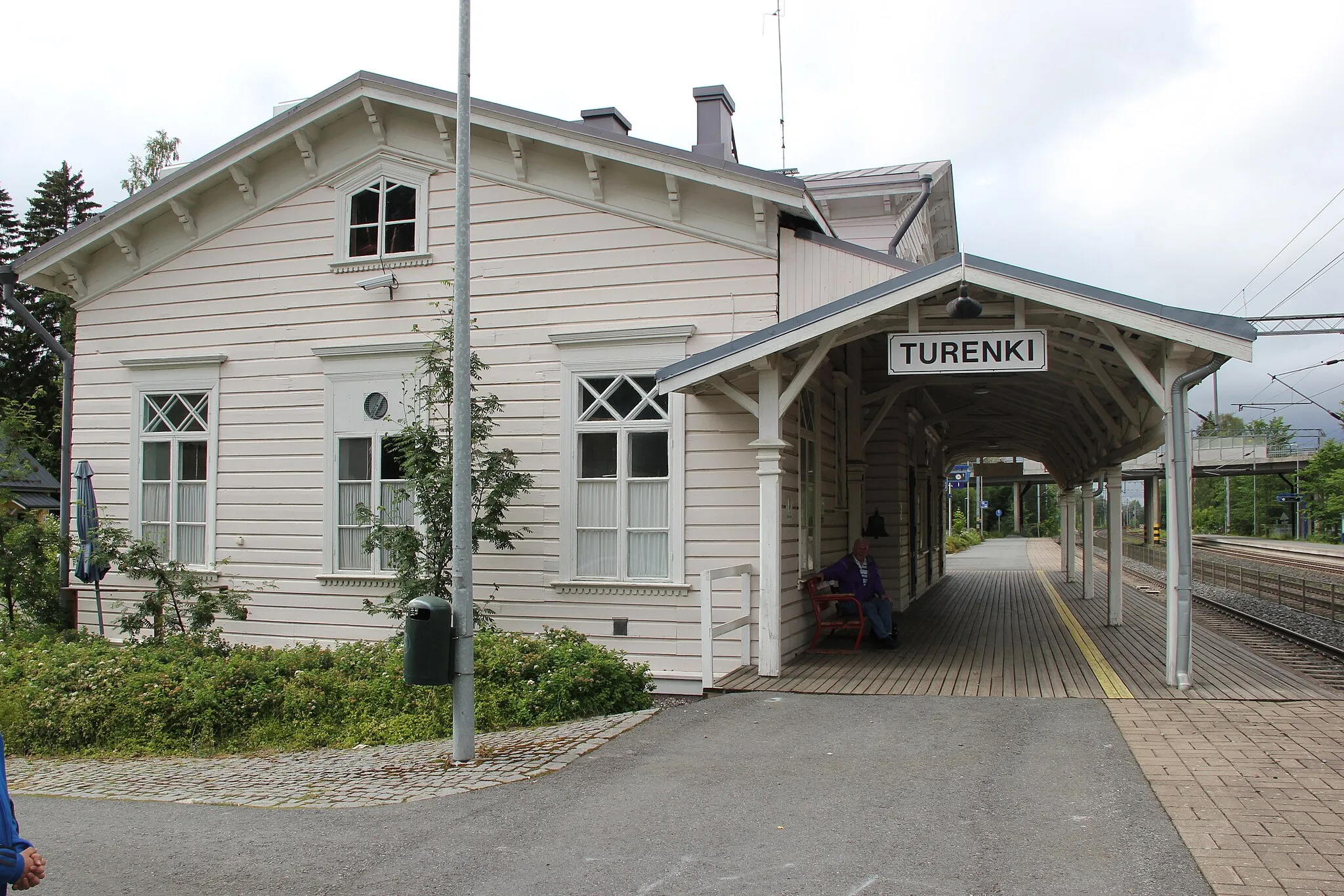 Photo showing: Railway station in Turenki, Janakkala, Finland. Architect: Carl Albert Edelfelt, 1862. Material: Wood. Nowadays: Restaurant.  The man sitting on the bench is a retired prison guard.