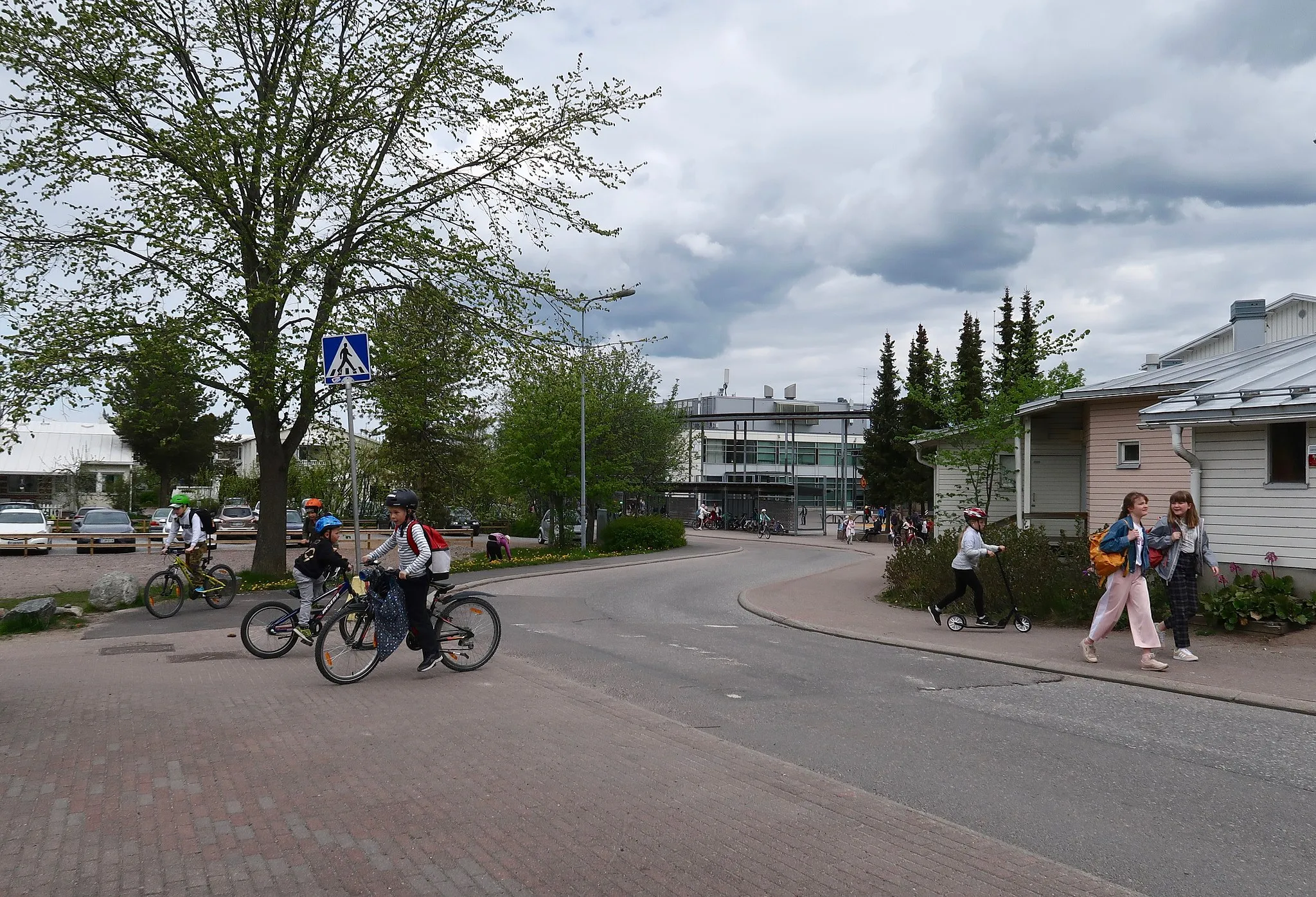Photo showing: Näkymä Ylä-Fallin tielle Torpparinmäessä. Keskellä Torpparinmäen peruskoulu, Ylä-Fallin tie 54. Tiellä kävelevät ja pyöräilevät lapset ja nuoret ovat koulun oppilaita. Koulupäivä on päättynyt.