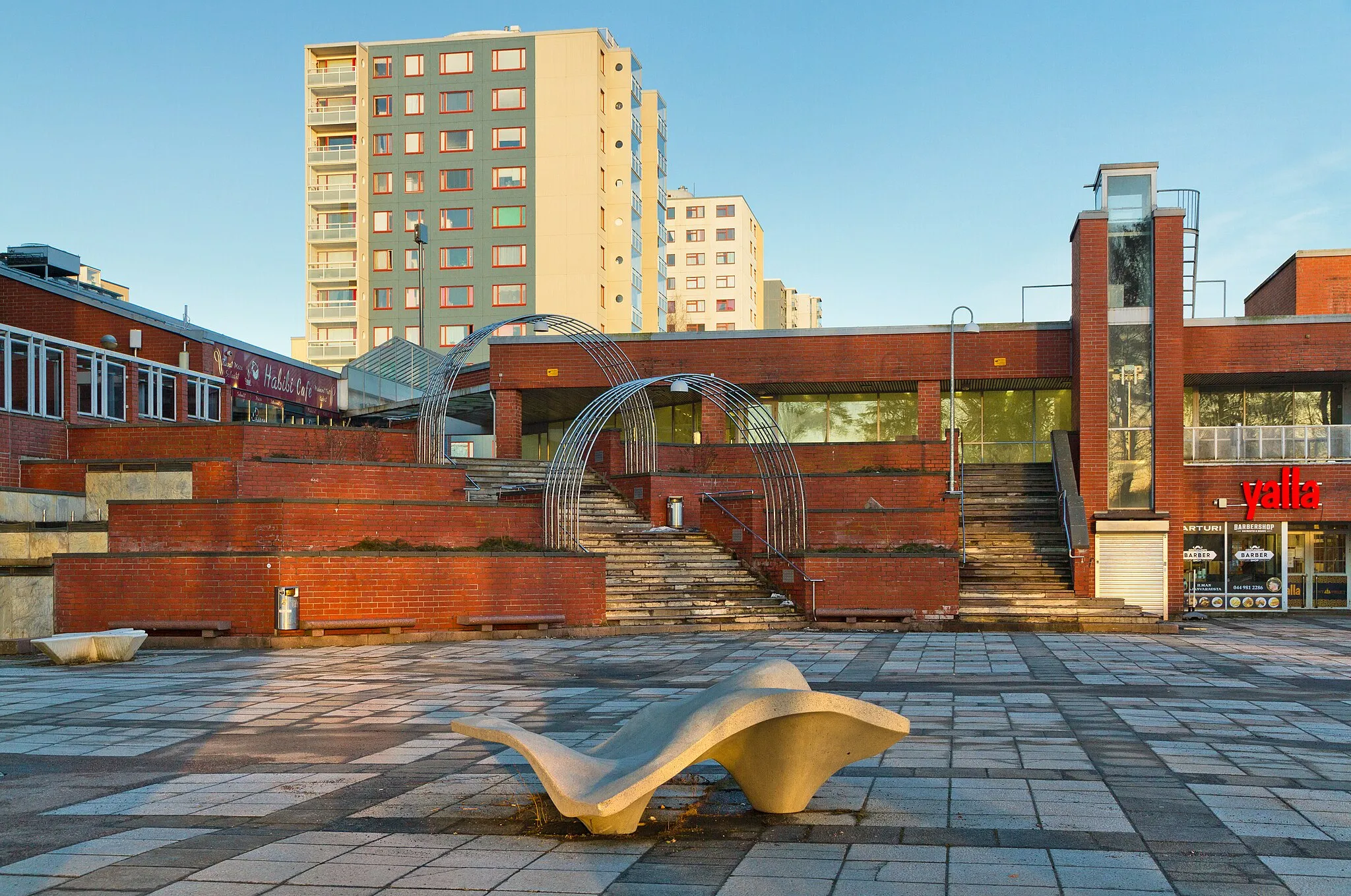 Photo showing: Koivutori plaza and Koivukylän ostoskeskus (a shopping center built in 1981) in Havukoski, Vantaa, Finland in 2021 March. The high apartment blocks rising in the background are from the 1970s.