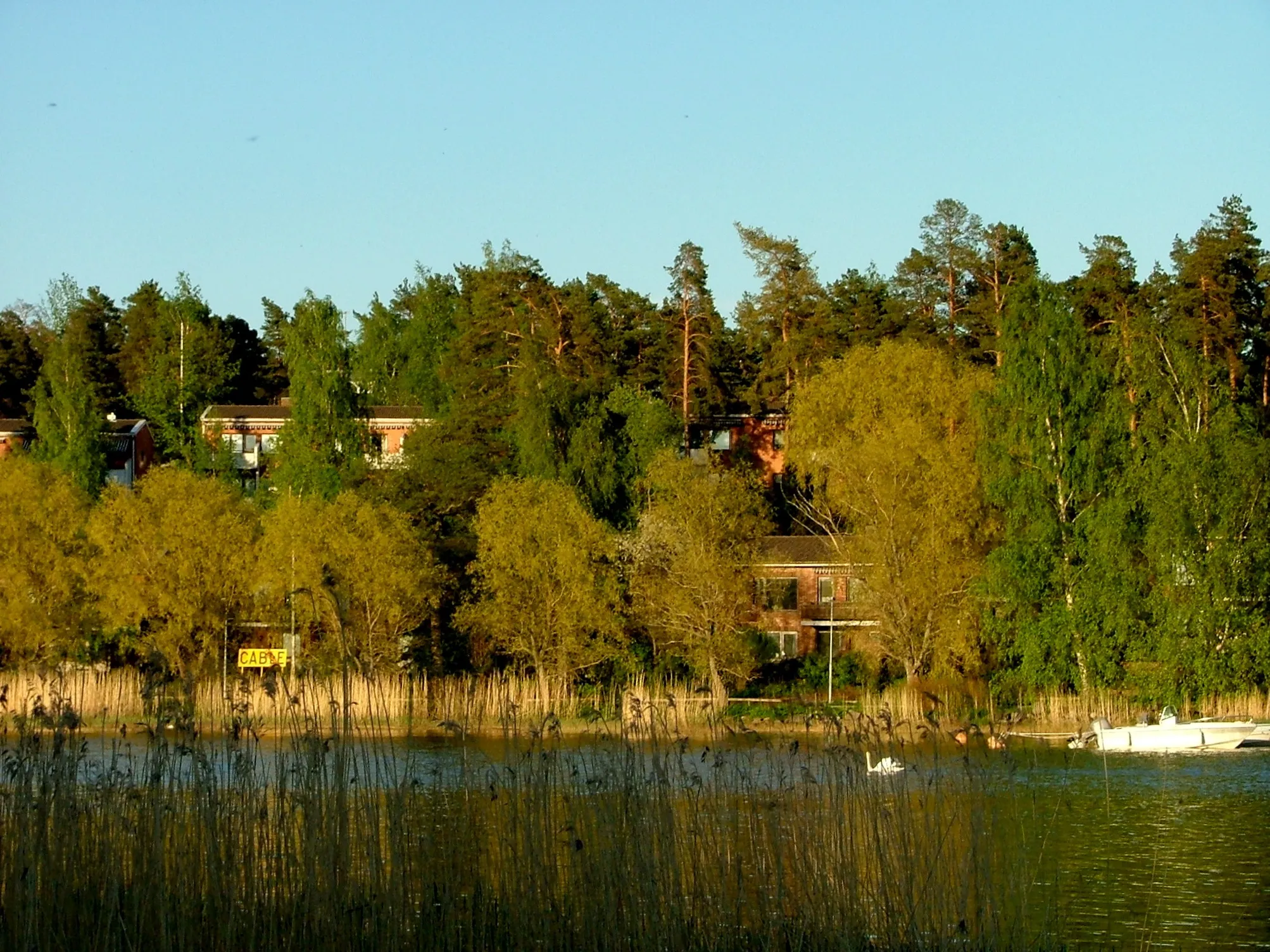 Photo showing: Residential houses on the seashore of Rastila district in Eastern Helsinki, Finland. Photographed from Vartioharju on the other side of the Vartiokylänlahti bay.