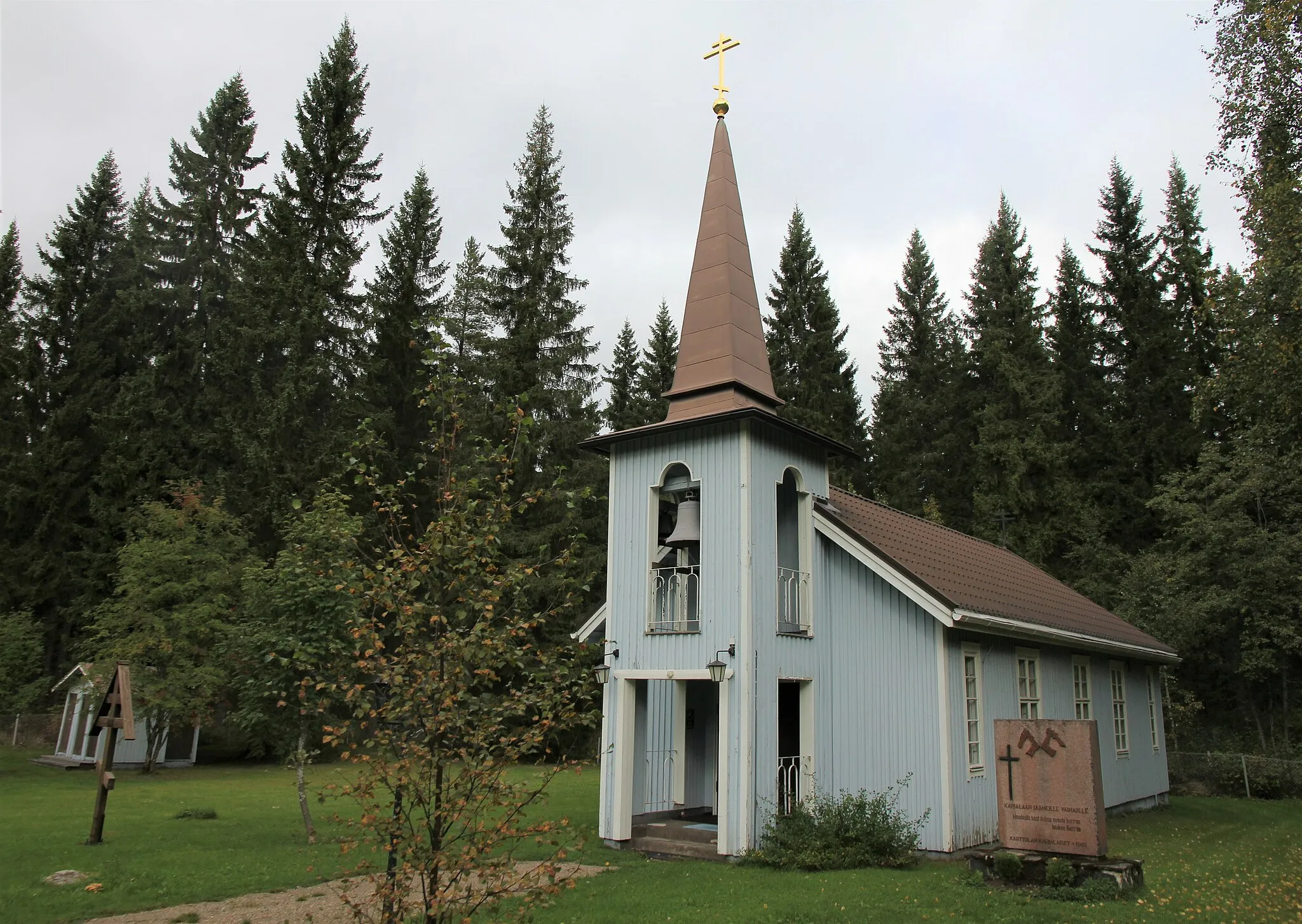 Photo showing: Syvänniemen ortodoksisen rukoushuone, eli Ylienkeli Mikaelin rukoushuone, on vuonna 1949 valmistunut, Kuopion ortodoksisen seurakunnan puurakenteinen rukoushuone. Se sijaitsee katuosoitteessa Mihailantie 8 (hieman Karttulantien pohjoispuolella), Kuopion Karttulan pitäjän Syvänniemen kylässä. Kirkon pihalla on kaksi muistomerkkiä: puisen matkamiehen ristin muotoinen Suomen sodan 1808–1809 Löttökosken 14.9.1808 taistelussa kuolleiden venäläissotilaiden muistomerkki ja punagraniittinen Karjalaan jääneiden vainajien muistomerkki (1961).