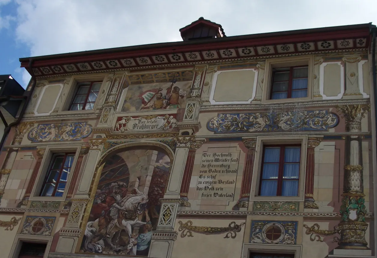 Photo showing: Der Rathskeller in Olten (Schweiz), rückseitige (grabenseitige) Fassade.
Das Gebäude stammt von 1673 und steht am Rande der Altstadt, an Stelle der ehemaligen Ringmauer. 
Es war ursprünglich der Gaststall der Herberge "zum Löwen", im späteren 19. Jh. zu einem Wohnhaus umgebaut mit Versatzstücken der ehemaligen Fassade des "Löwen". Ein Restaurant ist das Gebäude seit 1896 (zunächst unter dem Namen "Baselbieter"), umgebaut und "historisierend" ausgestattet 1905-6, seit damals "Rathskeller". Das Gebäude heisst auch "Kübel" (dialektal Chöbu, Chübu).[1]
Die Fresken auf der Fassade sind von Emil Kniep (1906). Auf der vorderen Fassade   "Auszug der Oltner in den Bauernkrieg 1653" (s. File:Olten03.jpg), rückseitig   "Der letzte Frohburger" [2]
http://www.rathskeller-olten.ch/

Die Wandmalerei zeigt den Grafen Eberhard von Frohburg auf seinem Ross, wie er auf der Aarebrücke vom Blitz erschlagen wird. Inschrift: "Der Hochmuth seinen Meister fand / die Herrenburg vom Boden schwand / Es schuf zu ewigem Bestand / das Volk sein freies Vaterland".[3] Die Frohburger waren bis zu ihrem Erlöschen im späteren 14. Jh.  die Herren von Olten. Ein "letzter Frohburger" Eberhard, der von Blitz erschlagen worden wäre ist legendär; der letzte Graf von Frohburg war Johann, gestorben 1366 (den Grafentitel erbte kurzfristig Hermann VI., Abt des Klosters St. Urban, der jedoch im Folgejahr ebenfalls verstarb).[4]