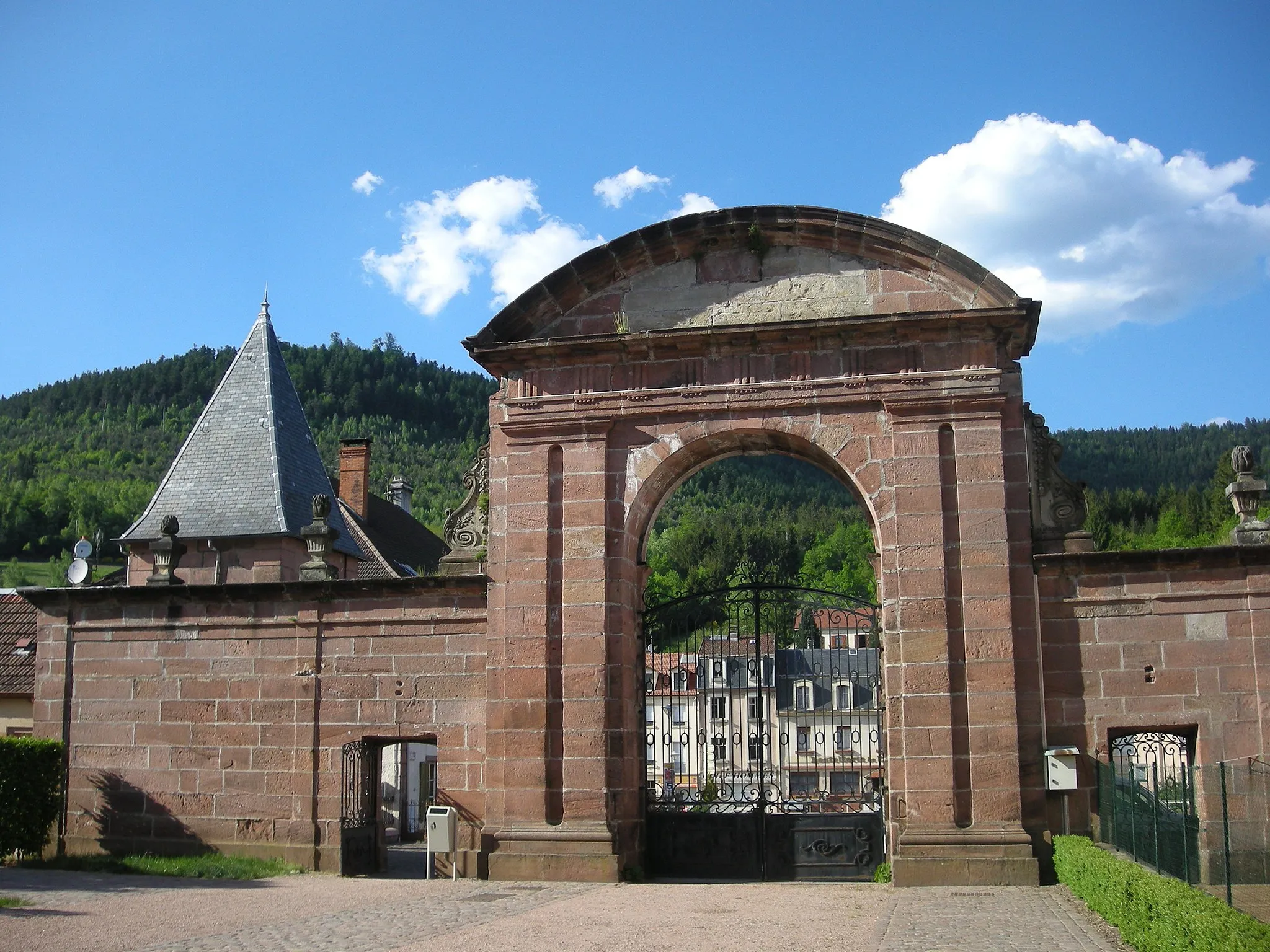 Photo showing: Portail d'entrée (XVIIIe siècle) - côté intérieur - de l'ancienne abbaye de Moyenmoutier (Vosges). Il est entouré de volutes en pierre blanche et surmonté d'un vaste fronton semi-circulaire, dont le linteau présente des motifs doriques repris sur l'ancienne porte d'entrée de l'église actuellement murée. A gauche, une tour d'angle.