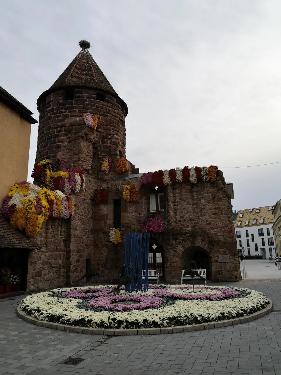 Photo showing: Der Storchenturm (erhaltener Rest einer mittelalterlichen Wasserburg) dazu im Vergleich während der jährlich im Herbst stattfindenden Blumenschau "Chrysanthema Lahr" im Jahr 2018.