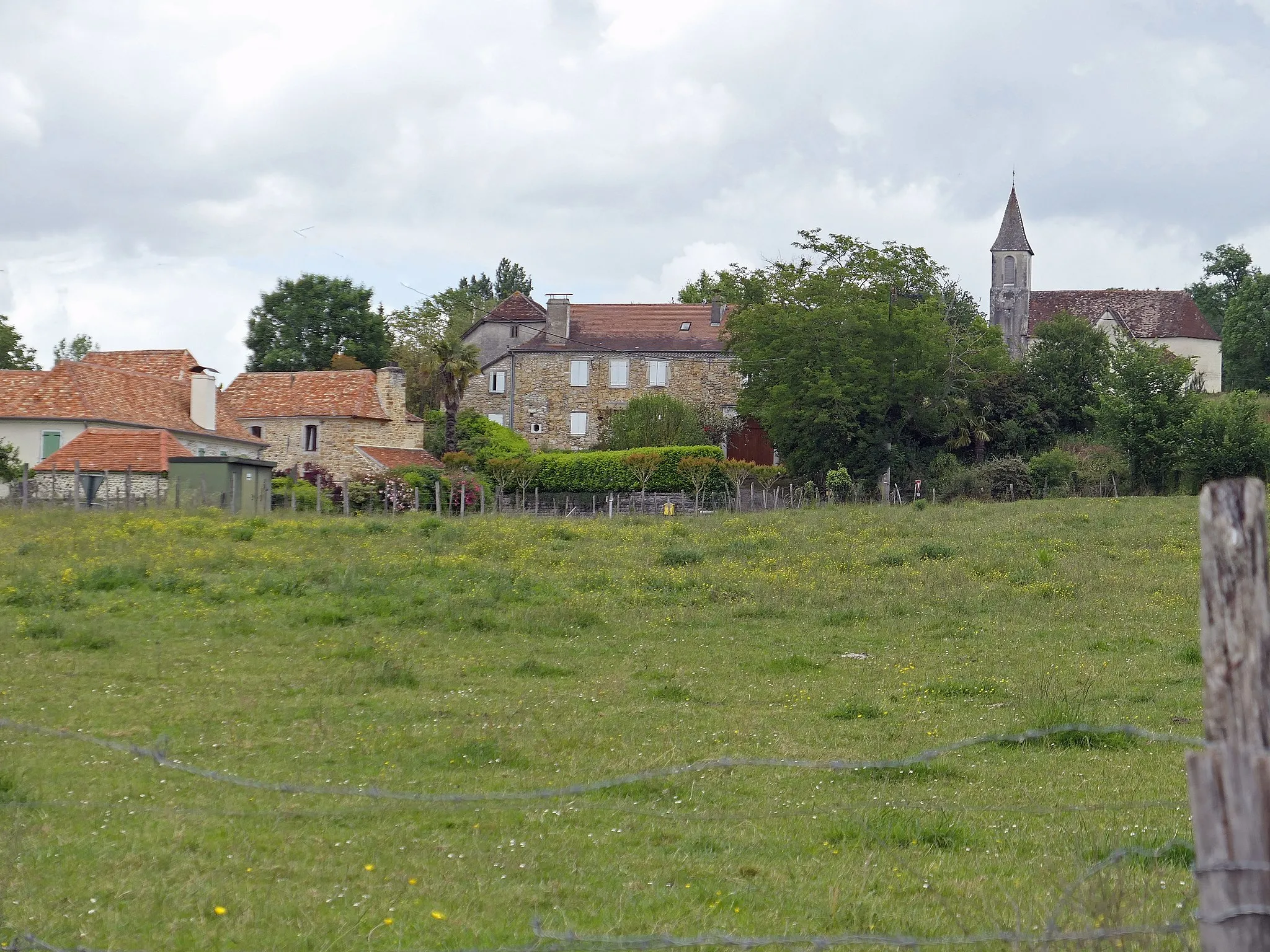 Photo showing: vue des champs sur des maisons couvertes en tuiles, église avec clocher flèche