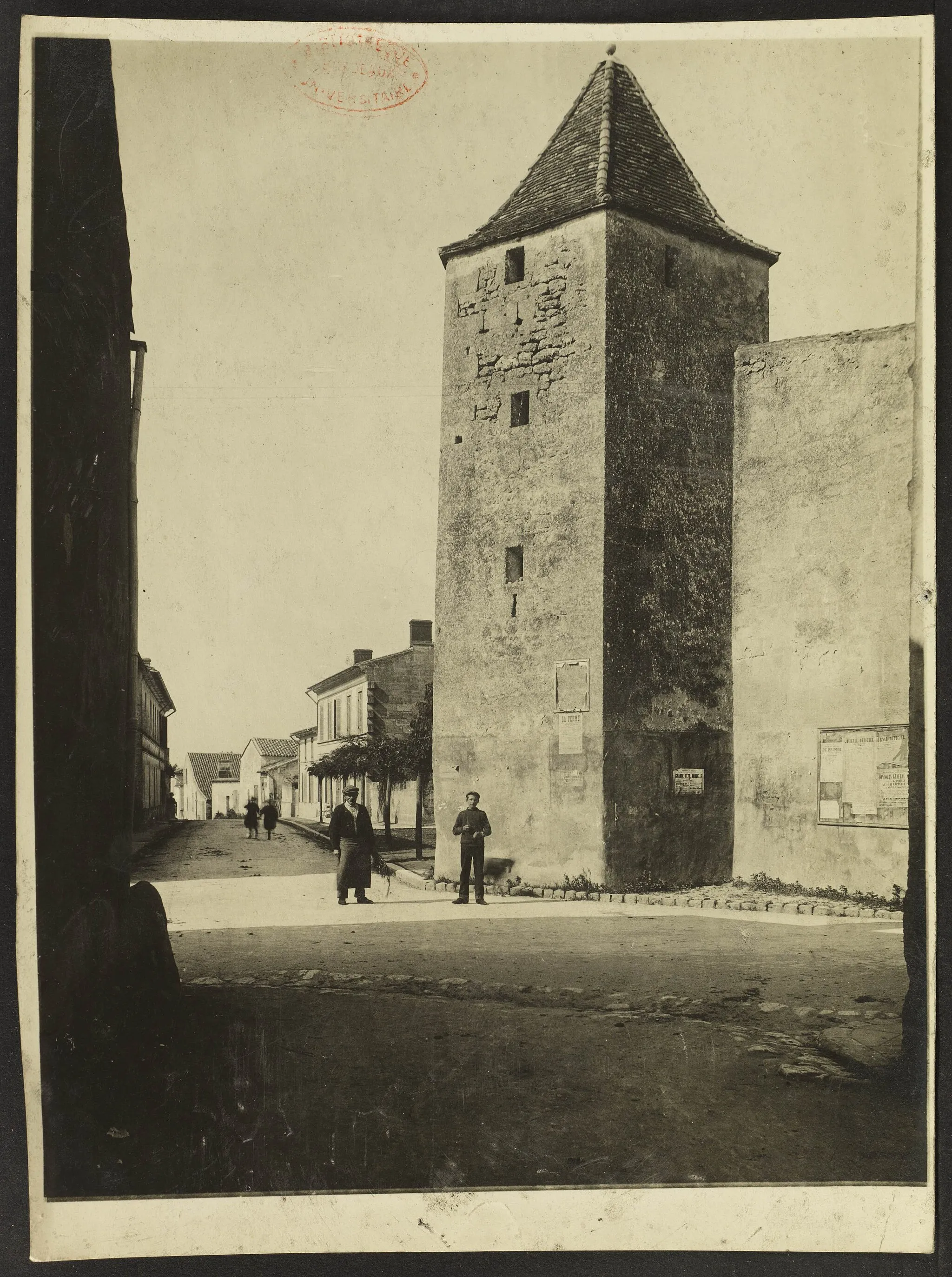 Photo showing: Deux hommes prenant la pose au pied d'une tour carrée à Saint-Antoine-de-L'Isle
