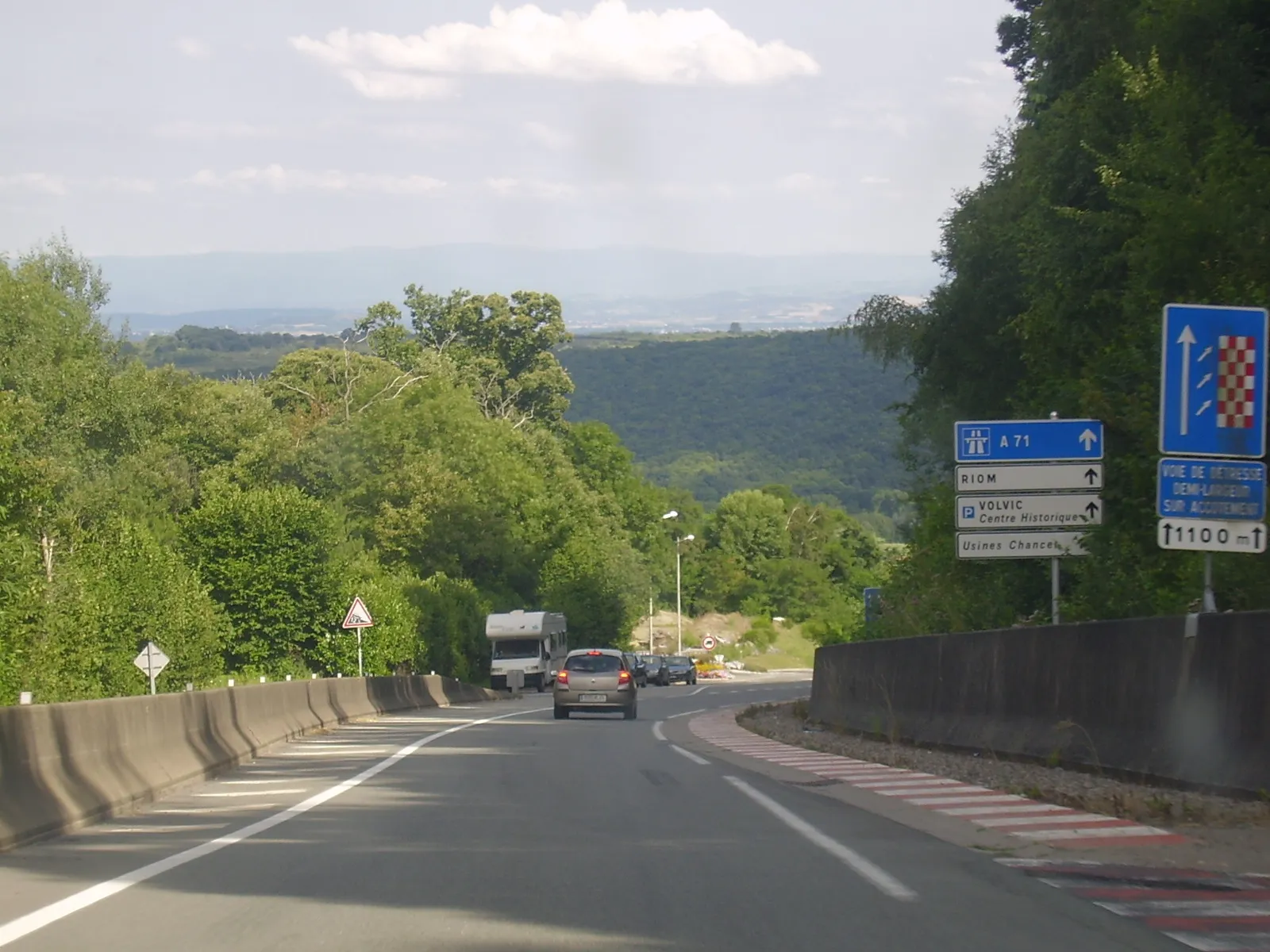 Photo showing: La RD 986 se dirige vers Riom, Volvic. Suite de la pente de 12 %. Sur la droite (panneau légèrement tronqué de justesse), la voie de détresse demi-largeur sur accotement sur 1 100 mètres. Cf. la voiture de devant (une Renault Clio III) qui ralentit.