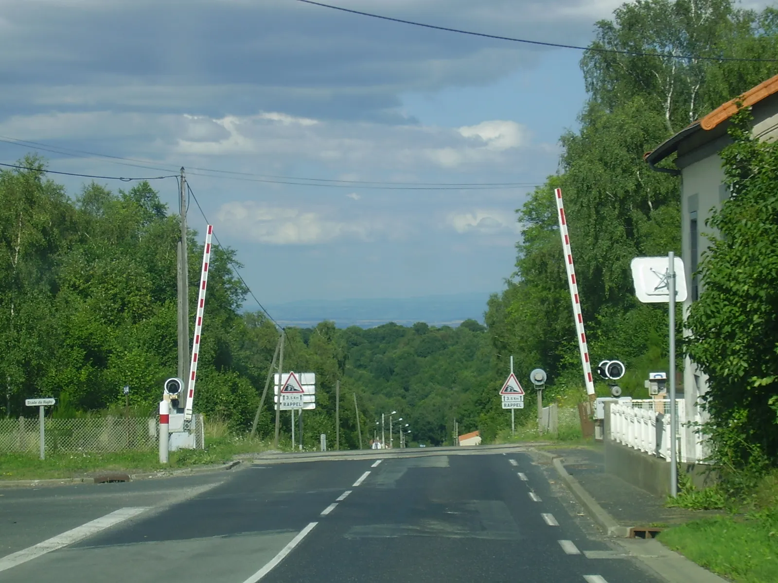 Photo showing: Passage à niveau sur la RD 986, au niveau du Cratère, commune de Volvic, Puy-de-Dôme, Auvergne, France. La route constitue un lieu sensible (pente de 9 % sur plus de 3 kilomètres). La route coupe la ligne d'Eygurande - Merlines à Clermont-Ferrand à deux voies (la gare de Volvic est accessible par un chemin à gauche).