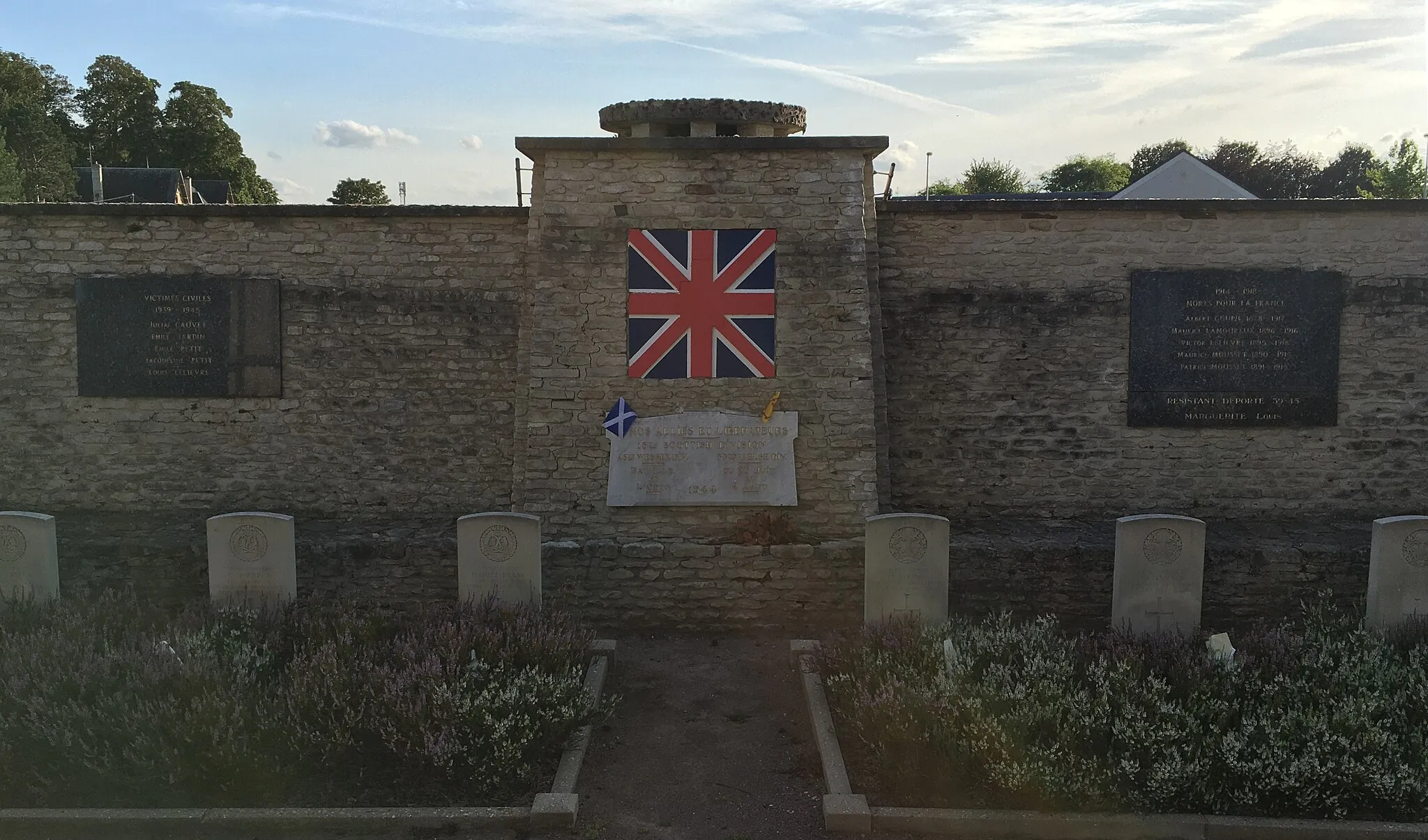 Photo showing: Memorial site dedicated to the 15th Scottish division involved in the battle of Odon, civilians who perish during the events and plaque commemorating local soldiers who died during WW1 and WW2. 6 British soldiers are also buried at the site