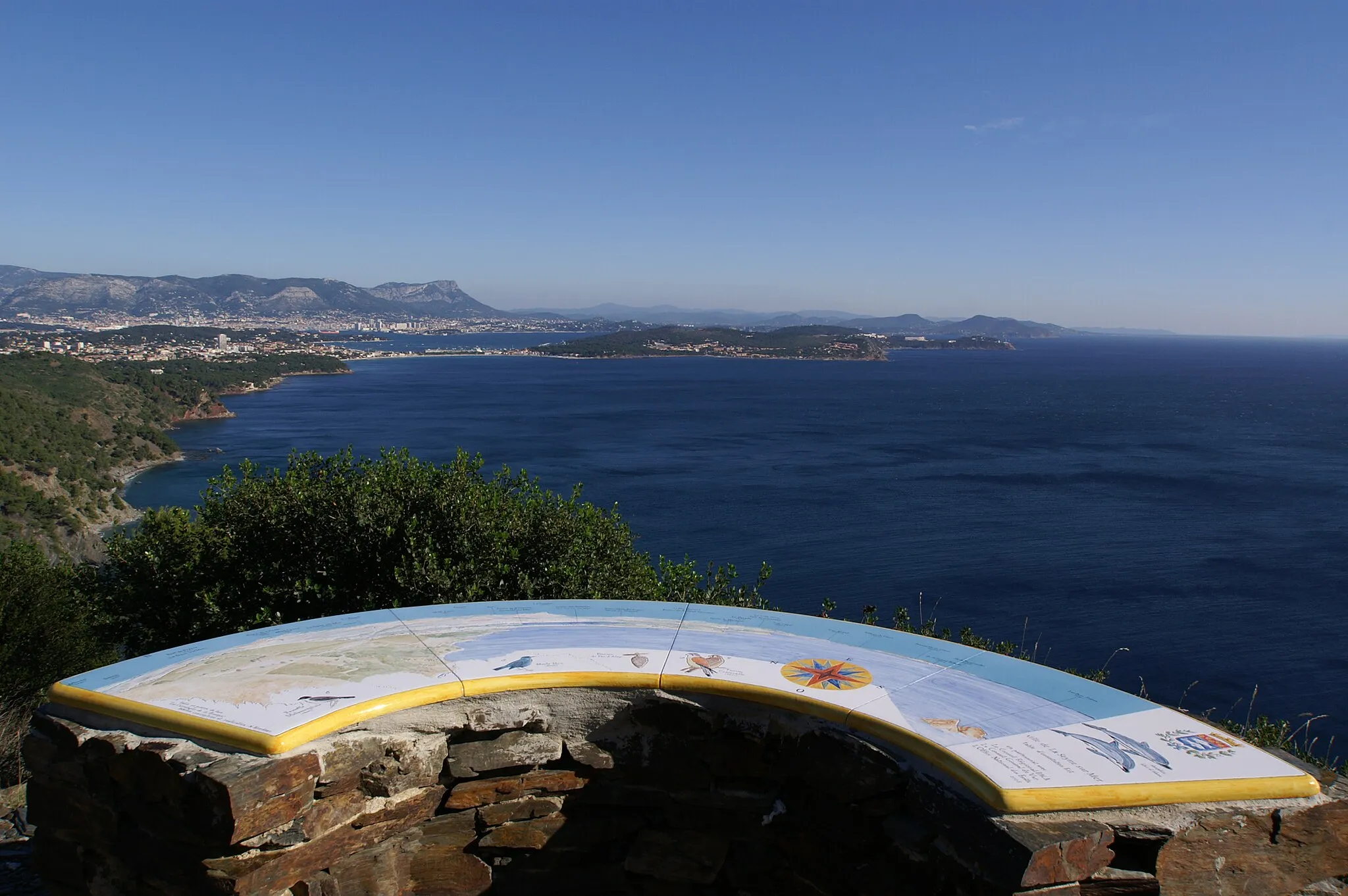 Photo showing: Table d'orientation située sur la colline du cap-Sicié, et d'où l'on peut voir de gauche à droite

au premier plan, la côte du Cap-Sicié à la plage des Sablettes (commune de La Seyne-sur-Mer) puis la presqu'île de Saint-Mandrier-sur-Mer.
à l'arrière plan, la ville de Toulon surmontée du mont Faron et du mont Coudon, et la côte qui se prolonge à l'Est avec les îles d'Hyères.