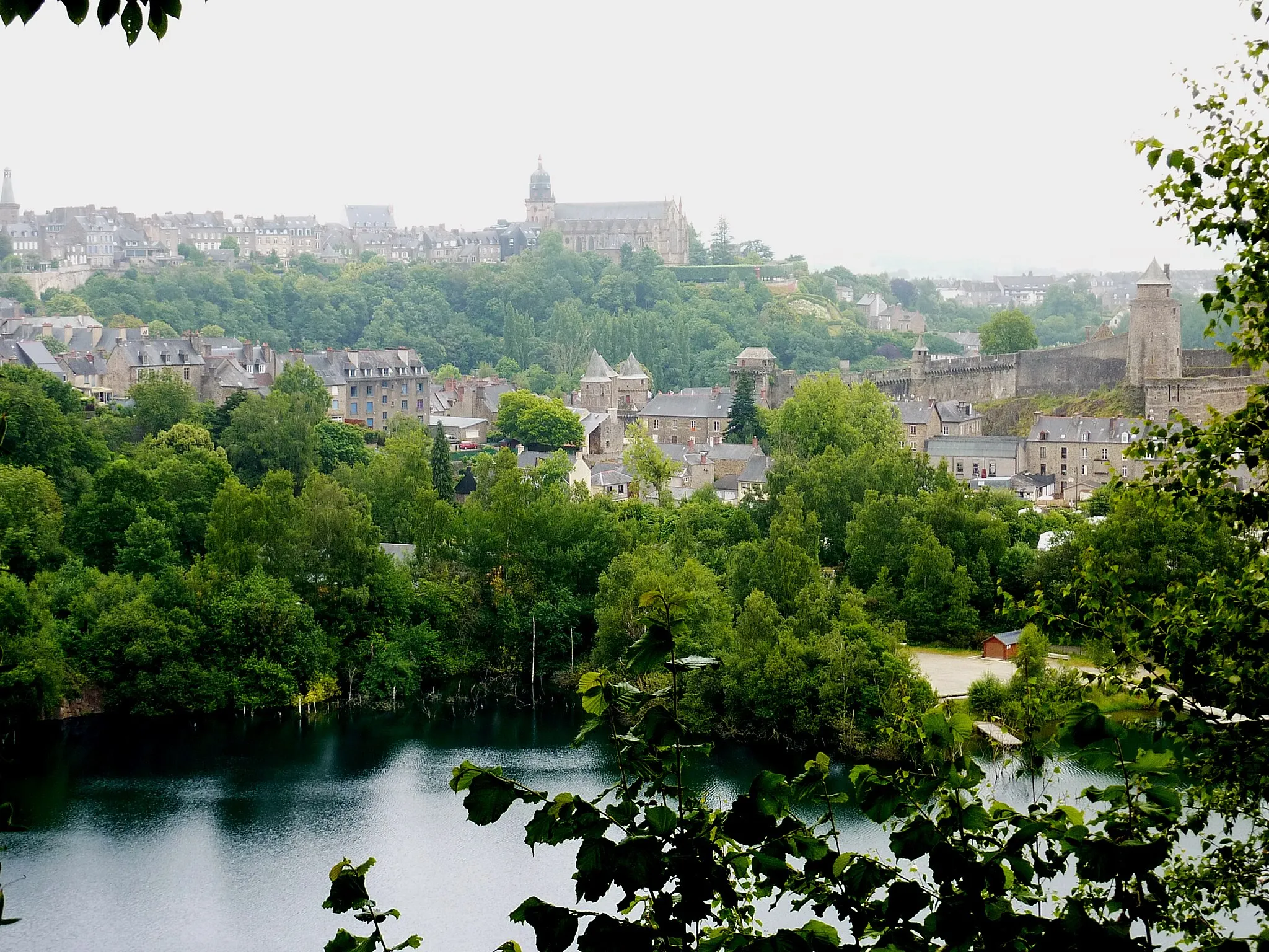 Photo showing: Fougères vu depuis le point de vue dominant le site du Rocher coupé (une ancienne carrière devenue un étang) situé sur la rive droite du Nançon.  À droite de la photo, le château de Fougères, et à l'arrière-plan de la photographie, l'église Saint-Léonard ; au premier plan, l'étang remplissant l'ancienne carrière.