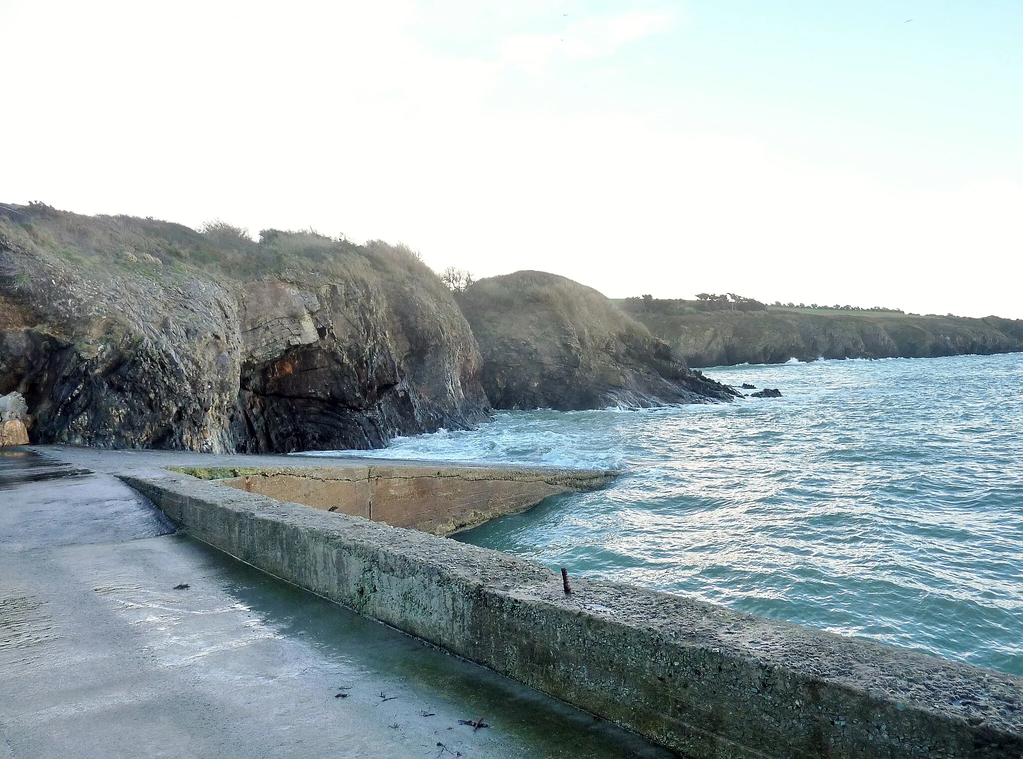 Photo showing: Saint-Nic : falaises et grottes au sud-est du petit port de Cameros (situé au premier plan) à marée haute.