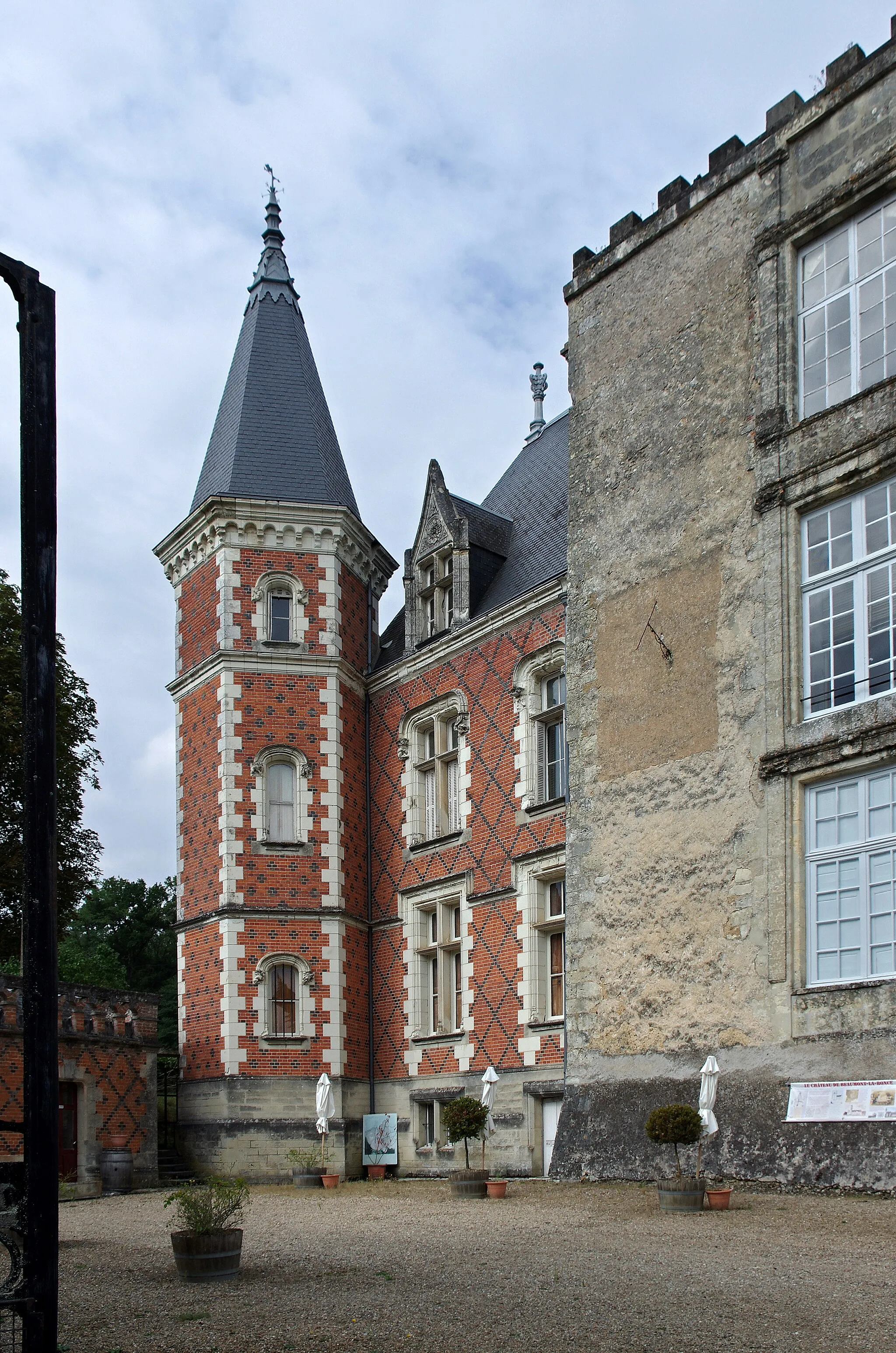 Photo showing: Beaumont-la-Ronce (Indre-et-Loire)

Le château domine vallée de La Choisille, il se dresse actuellement au coeur de la commune.
Le propriétaire actuel est affilié aux Ronsard : « C'est depuis les Daillons, Fromentières, Bueil, que ma famille est affiliée aux Ronsard, raconte Pierre de Beaumont. Le point d'orgue étant le mariage en 1534 de mon aïeule avec Philippe de Ronsard, maître des terres de Beaumont-la-Ronce et cousin du poète». (La Nouvelle République du 3/6/2016).

Pierre-de-Ronsard raconte dans son premier poème dédié à Marie de Bourgueil, «Les amoureux ou le Voyage de Tours», son passage au château de Beaumont-la-Ronce :
Thoinet* au mois d’Avril passant par Vandomois,
Me mena voir à Tours Marion que j’aimois,
Qui aux nopces estoit d’une sienne cousine :
Et ce Thoinet aussi alloit voir sa Francine,
Qu’Amour en se jouant d’un trait plein de rigueur,
Luy avoit pres le Clain escrite dans le coeur.
Nous partismes tous deux du hameau de Coustures,
Nous passasmes Gastine* et ses hautes verdures,
Nous passasmes Marré, et vismes à mi-jour
Du pasteur Phelipot* s’eslever la grand tour,
Qui de Beaumont la Ronce honore le village
Comme un pin fait honneur aux arbres d’un bocage.
Ce pasteur qu’on nommoit Phelippot tout gaillard,
Chez luy nous festoya jusques au soir bien tard.
De là vinsmes coucher au gué de Lengenrie*,
Sous des saules plantez le long d’une prairie.

Après avoir appartenu, au XIIe à un certain Giraud, puis aux familles Maumoine, Fromentières, Ronsard, Launay, Montigny, Levasseur, la seigneurie et le château de Beaumont-la-Ronce sont acquis par Claude Bonnin de La Bonninière en 1691, qui l’ajoute ainsi aux seigneuries de sa famille, les Beaumont, déjà seigneurs de Beauvais, des Châtelliers, du Fresne-Savary à Beaumont-la-Chartre etc.
L’ensemble sera érigé en marquisat en 1757*. (Conseil Général d'Indre et Loire - Fond de Beaumont - Isabelle Girard Attachée de conservation du patrimoine)
Tous les titres de féodalité, d’érection en marquisat ont été brûlés en 1793.
Le donjon carré, en pierres et en briques, couronné de machicoulis et de créneaux, fut achevé par le sieur Giraud vers 1108. Il était entouré de fossés et deux ponts-levis en permettaient l’entrée. Une échaugette ornait chaque angle. Le donjon avait quatre étages et était surmonté d’une guérite de pierre, dite chambre du nain, percée de quatre petites fenêtres dirigées chacune vers un des points cardinaux, et destinée au guetteur.
A la suite du donjon, existait un corps de logis couronné par une courtine à machicoulis qui reliait entre elles plusieurs tours aujourd’hui rasées.
Au XVIe siècle, on fit de grands changements. On ajouta une tour d’escalier octogonale, accolée au donjon,  et surmontée d'un toit aigu. Elle existe encore. Les baies et ouvertures furent remaniées et agrandies. On perça des fenêtres de deux pieds carrés et garnies de barreaux de fer. Dans la cour intérieure, on trouvait d’abord les étables, puis la boulangerie, le fournil,… Il y avait un puits dans cette cour. Le château communiquait avec la basse-cour par un des ponts-levis, plus petit que celui qui donnait accès au donjon. Dans la basse-cour, il y avait une grande étable, un pressoir, une grange, une fuie ou colombier féodal.
En 1786 on modifia beaucoup le vieux manoir. Pour obéir au goût de l’époque, le propriétaire commença à démolir le donjon dont il abattit les machicoulis, les créneaux et un étage. La démolition fut arrêté  pendant la Terreur ce qui sauva le reste de la tour. Le maître maçon local Gripouilleau remania la façade nord dans le style Louis XVIII.
Au XIXe siècle, côté église, fut ajouté une aile de style renaissance à revêtement de briques, et une construction augmentée d’une chapelle, imitation renaissance, remplaça une partie de l’aile nord qui commençait à se fissurer. Ces deux adjonctions sont l’œuvre des grands architectes tourangeaux Guérin père et fils. (Commune de Beaumont-la-Ronce site communal)

Thoinet : Jean-Antoine de Baïf, poète et ami de Ronsard, membre de la Pléiade. Il est né à Venise, étant fils naturel de Lazare de Baïf, ambassadeur à Venise au moment de sa naissance. Joachim Du Bellay le qualifiera de "Docte doctieur et doctime Baif", ce qui n'était pas ironique. La forêt de Gastines était une forêt du Nord de la Touraine. Il en reste la forêt de Beaumont-la-Ronce et le bois de Gâtines à Montrouveau (Loir-et-Cher), près de Montoire. Il s'agit du cousin Philippe de Ronsard, seigneur de Beaumont, qui eut d'un premier lit deux fils, Jean et Jean-Baptiste. Ce sont les deux fils de Philippe, qui manigancèrent avec leurs cousins, Nicolas-Horace et Gabriel, l'assassinat de Magdelaine-de-Monceaux, originaire d'Auvergne, qui avait épousé Guillaume-de-Ronsard. Guillaume, héritier de la Denisière, avait épousé, le 6 février 1559, Madeleine de Monceaux avant de mourir sans postérité en 1567; il laissait l'usufruit de ses biens à sa veuve. 
Mécontents, Nicolas-Horace et Gabriel s'assurèrent, avec promesses de partage, la complicité de deux autres parents, Jean et Jean-Baptiste, ainsi que d'un fermier de Magdelaine, René Doré, en vue de liquider l'obstacle à leurs ambitions. 
Les conjurés choisirent un moment où celle-ci n'avait pas d'autre compagnie que quelques domestiques, le jeudi 14 mai 1573 dans la nuit. A l'exception de Nicolas-Horace resté prudemment au Mans, ils s'introduisirent en armes à La Denisière, et commencèrent par massacrer les gens de maison, avant de s'en prendre à Magdeleine. A force de violences, ils lui extorquèrent la cachette de son argent, puis, ils la tuèrent.
De retour à Beaumont, ils partagèrent le butin. Quand l'assassinat fut public, ils feignirent la plus grande douleur et prévinrent les deux frères de la victime, et tout le monde accourut à La Denisière. Faute de piste, l'affaire aurait pu rester non élucidée ou être attribuée à quelque rôdeur. 
René Doré tombé gravement malade, craignant pour son âme, avoua alors sa participation au crime. Finalement guéri, on l'éloigna au Mans, mais celà ne fut pas suffisant pour étouffer les bruits qui commencèrent à courrir. 
La famille de Monceaux usa de sa forte influence pour relancer l'enquête et faire rechercher les coupables. 
On arrêta Jean, l'aîné des Beaumont et un certain Beauclerc qui avaient gardé les chevaux pendant le forfait; ils furent exécutés, avec René Doré, place du Martroi à Orléans le 15 février 1574. 
Les trois autres principaux coupables, en fuite, condamnés à la roue par contumace, ne furent exécutés qu'en effigie.
Nicolas-Horace (le poète; il était paraît-il "excellent pour la musique au jeu du luth...),  attendit dix ans pour être rattrapé, en 1584, et eut la tête tranchée en place de Grève à Paris. 
Jean-Baptiste, le cadet des Beaumont, fut également rejoint par la Justice. Seul Gabriel, le clerc, aurait réussi à s'échapper.
La Denisière et ses dépendances furent enlevées aux Ronsard pour être remises aux Monceaux à titre de dédommagement.

Maintenant Langennerie, près de Chanceaux-sur-Choisille. L’union et l'érection en marquisat des terres et seigneuries de Beaumont-la-Ronce et des Châtelliers ont été accordées par lettres patentes du mois d’août 1757 en la faveur de Jean-Baptiste-Claude de Beaumont. Celui-ci possédait également les terres de Saunay, Fontenay, Les Matras, Guigny et Le Plessis-Bouchard. www.beaumontlaronce.fr/historique/le-chateau/
archives.cg37.fr/UploadFile/GED/SerieJ/1252058813.pdf

www.lemille-pattes.com/2015/07/les-crimes-des-ronsard-sui...