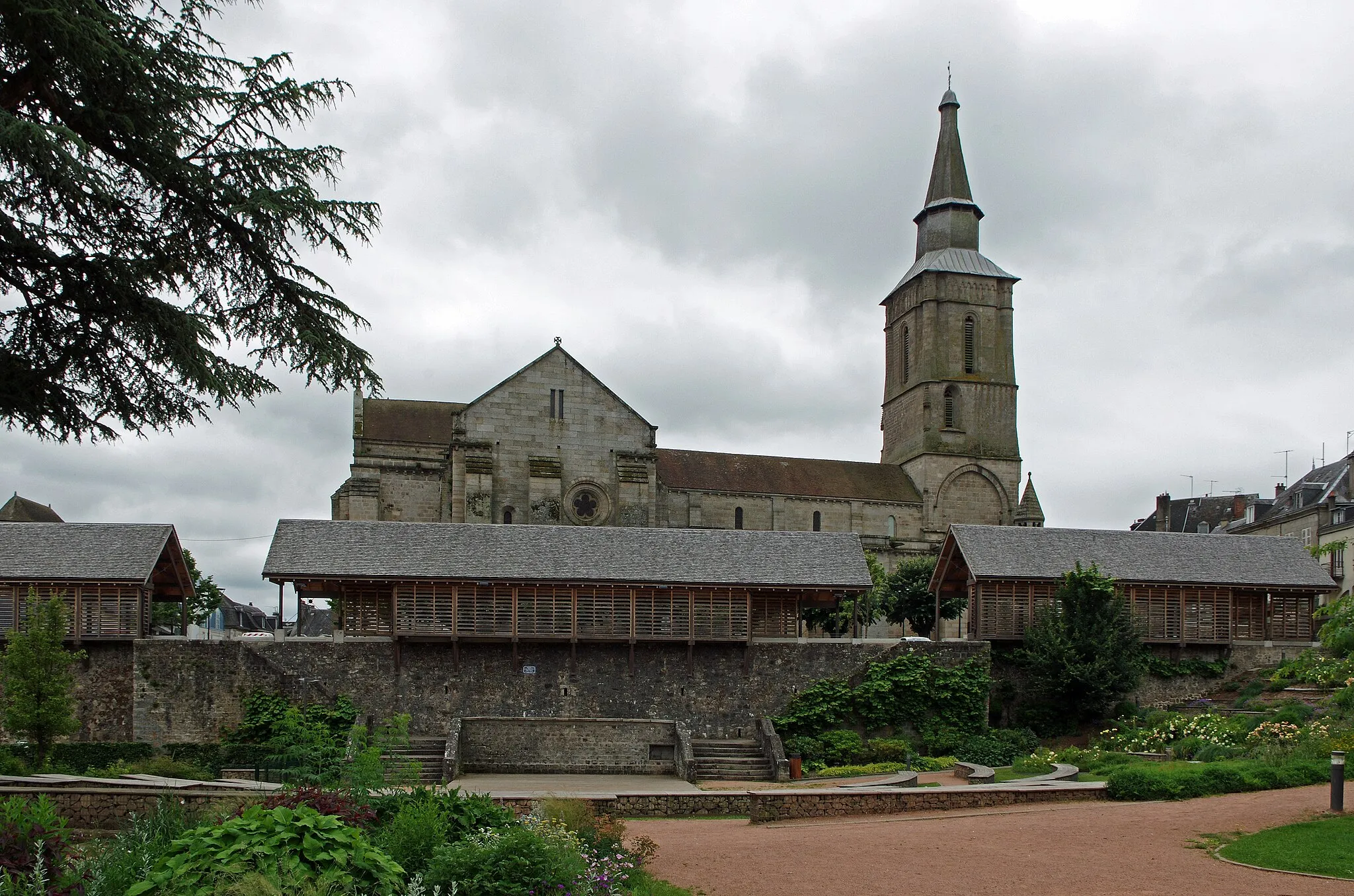 Photo showing: La Souterraine (Creuse).
Eglise Notre-Dame.
L'église Notre-Dame (De son vrai nom église paroissiale de l’Assomption-de-la-Très-Sainte-Vierge),se situe sur un des chemins menant à Saint Jacques de Compostelle. L'édifice a été restauré par l'architecte Abadie au milieu du XIXème siècle.
La collégiale romane, chef-d'œuvre de transition du roman vers le gothique. Restaurée par Abadie au XIXe siècle, elle conserve une crypte, construite par les moines de l'abbaye Saint-Martial de Limoges aux environs de 1020 pour servir de sépulture au fondateur Gérald de Crozant.
Juste après l'An Mil, Gérald de Crozant* fait don* d'une villa (Villa Sosteranea) à l'Abbaye Saint Martial de Limoges. Celle-ci y crée un Prieuré dont le premier prieur est Rodolphe Barton. Les moines de l'abbaye Saint Martial prennent possession d'un sanctuaire souterrain issu d'une nécropole gallo-romaine,  et la christianisent avec une relique de la vierge, ce qui attire de nombreux pèlerins.  La crypte agrandie et transformée* en une église souterraine comprend trois chapelles dont une héberge deux sarcophages d'époque gallo-romaine. Les moines utiliseront la crypte pour y placer la sépulture du donateur. Les moines entreprirent aussi la construction de l'église Notre Dame* qui dura deux siècles et est achevée au début du XIIIème siècle, vers 1230*.
La première partie, les deux premières travées de la nef, sont de style Roman. Le clocher, les trois dernières travées de la nef le transept et le choeur sont de style Gothique.
Le Portail principal est remarquable avec ses trois voussures polylobées d'inspiration mozarabe. Il témoigne du brassage de populations et du passage des pèlerins de Saint Jacques provoquant le mélange des styles avec des apports en provenance d'Espagne. Chaque voussure comporte une partie plane et un tore tous deux festonnés.
Le clocher est rectangulaire à trois étages, il est du XIIIème siècle, remanié au XVème et le beffroi du haut est postérieur. Il mélange les styles car sa construction d'origine a subi de nombreux rajouts, à l'instar de la lanterne et de la flèche recouverte de bardeaux.
Le premier étage présente une grande arcade sur chaque face, les baies du deuxième étage sont inégales et le troisième n'a que deux baies avec des tourelles d'angles. 
Le chevet est plat et soutenu par de puissants contreforts, de même que les bras du transept.
Une crypte ancienne est située sous le choeur, elle est voûtée en ogives. On y a retrouvé les traces d'un édifice Gallo-Romain.

Gérald de Crozant, vicomte de Bridiers. On croit Gérald de Crozant neveu de Bernard Ier comte de la Marche. D'après le chroniqueur Geoffroy de Vigeois (Geoffroy de Breuil devient prieur de Vigeois à partir de 1178), vers 1017, Géraud (francisé, selon les auteurs, en Gérald ou Gérard), comte de Crozant, vicomte de Bridiers, vassal du Duché d'Aquitaine, fit don de la "Villa Sosterranea" (village de La Souterraine) à l'Abbaye Saint-Martial de Limoges. Les premiers travaux ne concernant que la crypte démarrèrent en 1017 et durèrent 5 ans. Le nom "La Souterraine" en découle. La construction de l’église haute débuta vers le milieu du XIIe siècle et ne fut achevée que mi-XIIIe siècle. L’église mélange ainsi différents styles : roman (au niveau des deux premières travées de la nef) et gothique (transept, chœur, clocher et les trois dernières travées de la nef). Développée en prieuré et prévôté monastique de Saint-Martial au début du XIIIe siècle – ce dont témoigne un autre chroniqueur limousin, Bernard Itier – La Souterraine contrôlait une douzaine de paroisses dans le diocèse de Limoges.