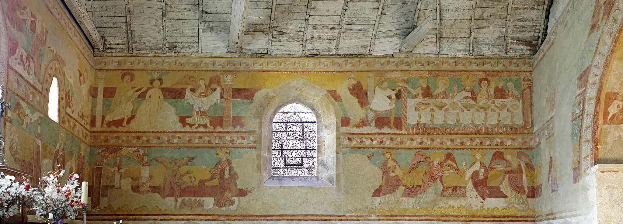 Photo showing: Brinay (Cher)
Eglise Saint-Aignan.
Les fresques du XIIe siècle ont été redécouvertes au début du XXe siècle par le peintre André Humbert. Elles couvrent les quatre murs du chœur.
La fresque de la face inférieure de l'arc du chœur représente les travaux des mois. Le départ pour la chasse pour le mois de mai, le sacrifice du cochon pour le mois de novembre, la moisson en juillet, le battage du blé au fléau en août, la fenaison en juin, le nourrissage des cochons avec  des glands en octobre...
Sur le mur Ouest, de part et d'autre de l'arcade, les figures sont très effacées. On reconnaît le prophète Jérémie dont un verset des Lamentations, "Il bande son arc et me prend pour cible avec sa flèche (3, 12)", est illustré par un homme couché qui essaye de retirer une flèche de son talon.
La fresque du mur Nord illustre l'enfance de Jésus avec : L'Annonciation, la Visitation, la Nativité, l'Annonce aux bergers, la venue des Rois mages incomplète (il manque les scènes de l'Adoration et du Songe).
Sur le mur Est, la partie supérieure, de part et d'autre de la fenêtre, représente le massacre des Saint-Innocents. En dessous à gauche, est représenté Jésus au temple. Joseph porte les colombes offertes en sacrifice pour la purification de la Vierge. Le sage Siméon tient l'enfant dans ses bras. A droite en bas, la fuite en Egypte. Joseph conduit la Sainte Famille, Jésus lui tend les bras.

Sur le mur Sud, les noces de Cana, la chute des idoles d'Héliopolis à l'arrivée de Jésus, et la tentation au désert.