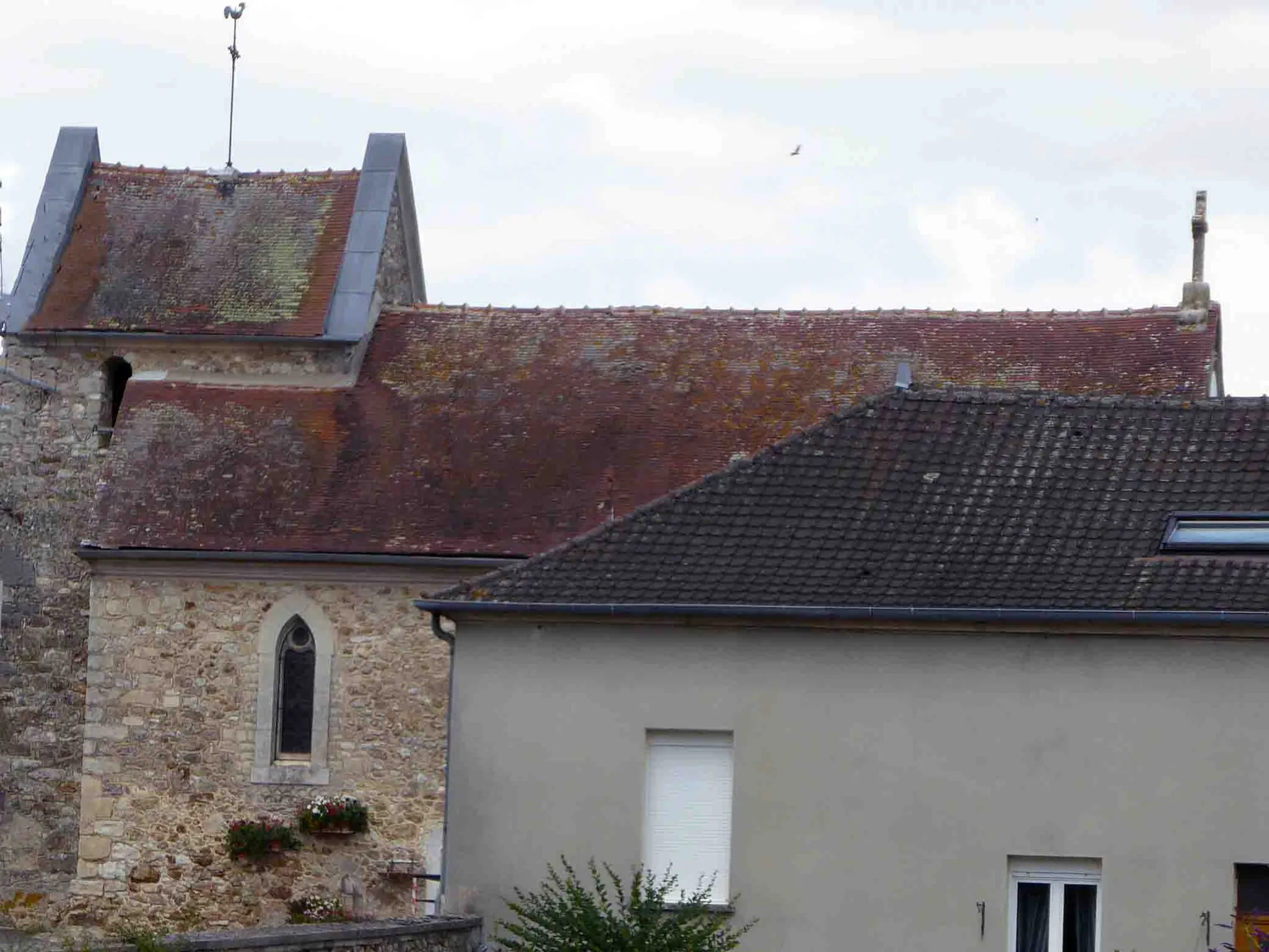 Photo showing: Aperçu de l'église derrière une maison: massive : tour carrée, clocher batière , couverte en tuiles